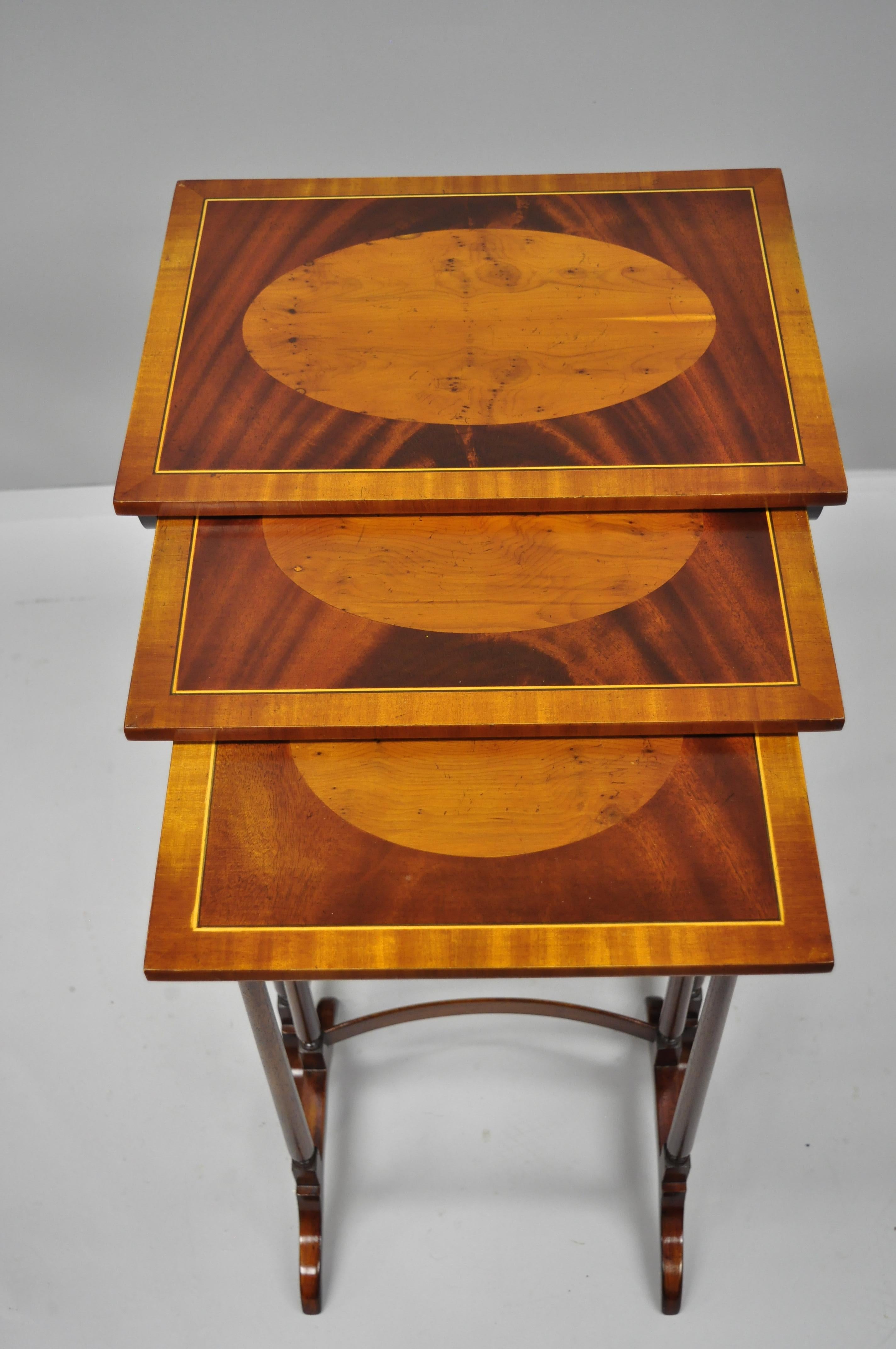 3-tier inlaid nesting side tables in yew wood and mahogany. Listing features pencil inlaid tops, beautiful yew wood and mahogany grain, bowed stretcher, 3 graduating sizes great style and form, circa mid-late 20th century. Measurements: 

27.5