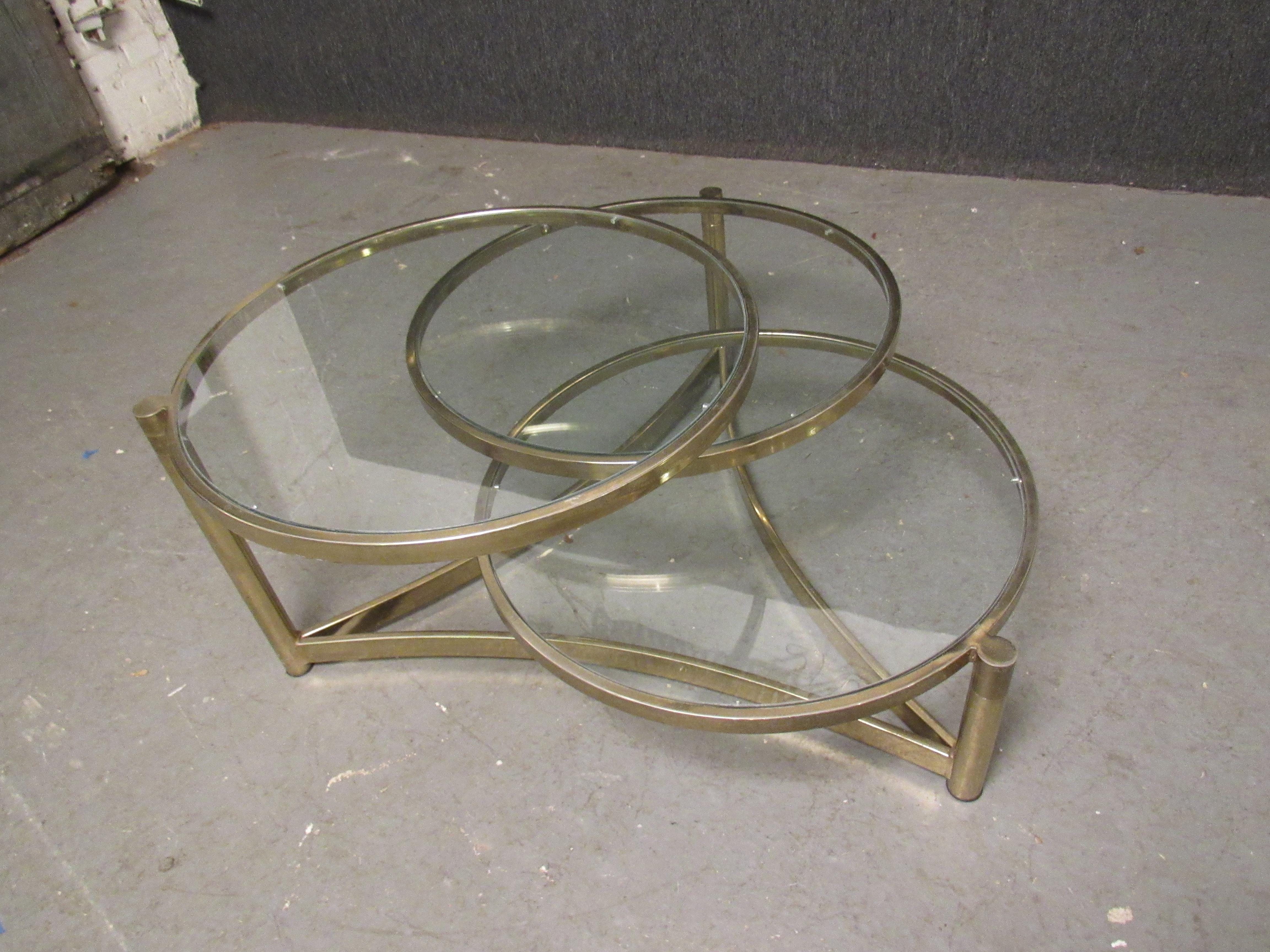 Iconic brass and glass articulated coffee table designed by Milo Baughman- this impressive modernist piece is versatile in so many ways- blending aesthetic stylings of Mid-Century Modern, Post-Modern, Hollywood Regency, and beyond. It's soft brass