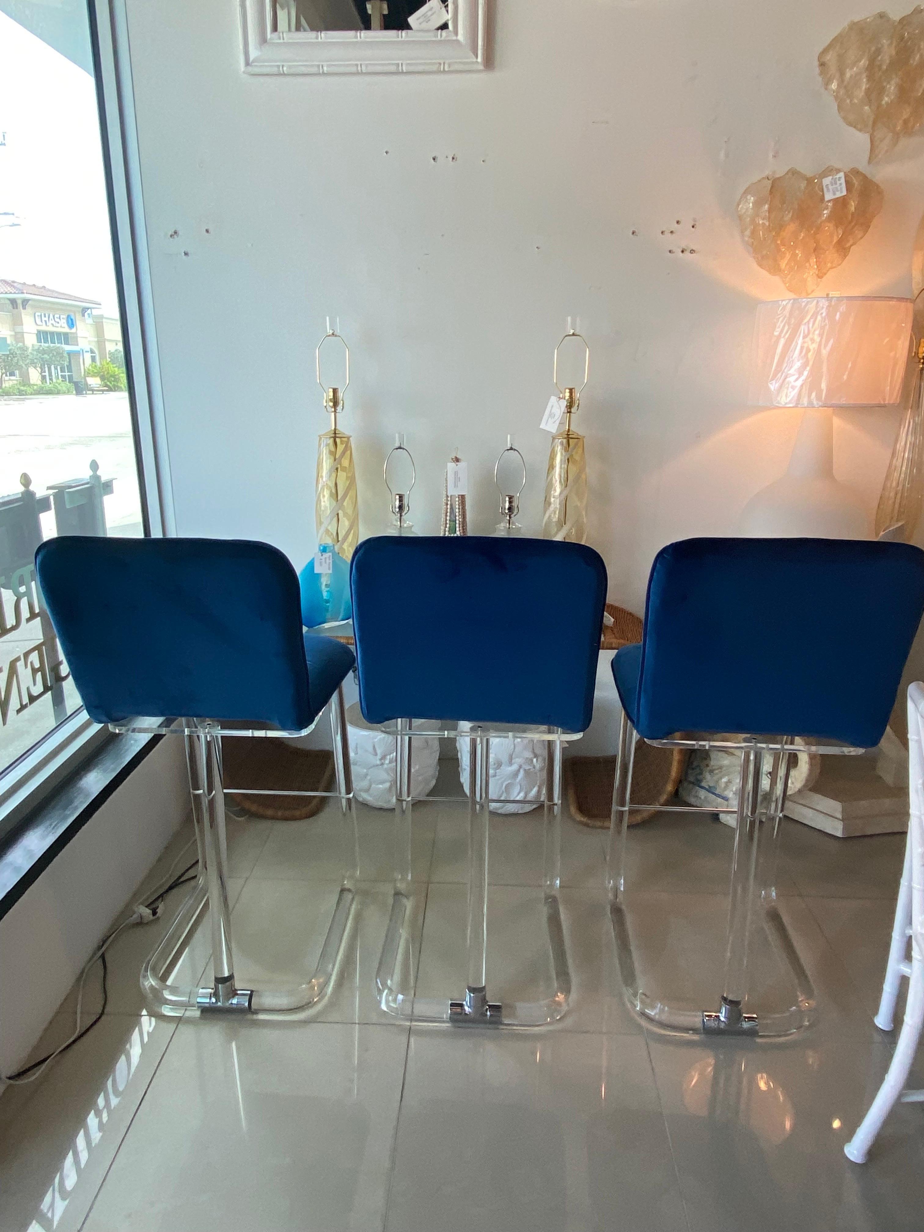Lovely set of 3 vintage, signed Lion In Frost barstools stools. Swivel seat. Lucite & Chrome with newly upholstered blue velvet seats. These have been polish and may have minor imprecations to the lucite and chrome. Dimensions: 43 H x 21 Deep x 19