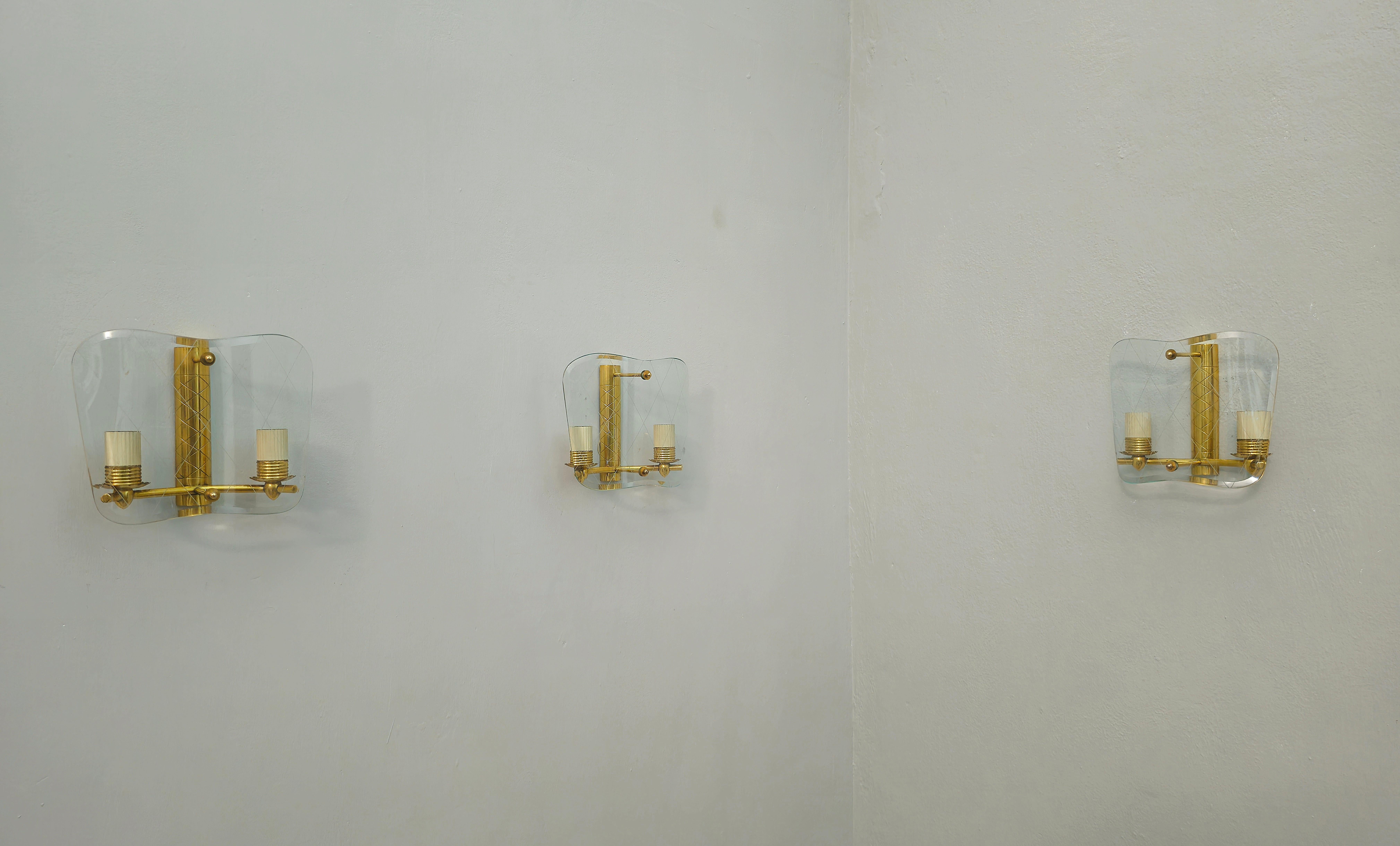 Set of 3 wall lamps produced in Italy in the 1950s. In the style of Emilio Lancia. Refined and elegant.
Each single wall lamp was made with a golden brass structure that supports a curved and decorated glass. Each single sconces has 2 E14 lights.