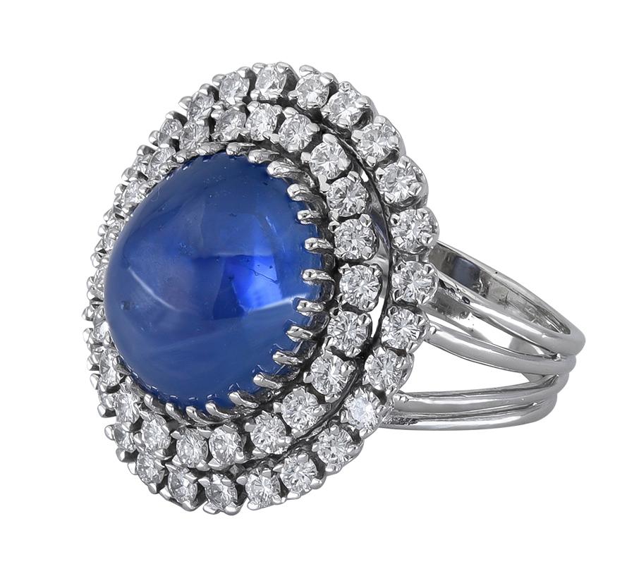 A rare and important piece of jewelry showcasing a single large cabochon blue sapphire, surrounded by two rows of round brilliant diamonds. Set in an 18k white gold mounting.
Blue sapphire weighs approx. 30.00 carats with certificate