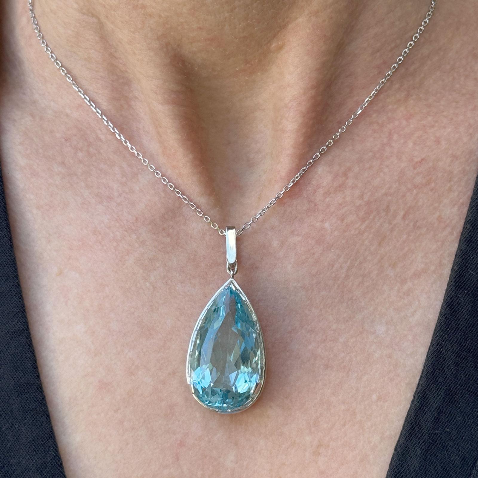 Ce superbe pendentif est orné d'une aigue-marine taillée en poire d'environ 30 carats, sertie dans du platine, dont l'éclat bleu océan est captivant. Autour de la pierre centrale, 28 diamants taille baguette totalisant environ 0,80 carat (couleur