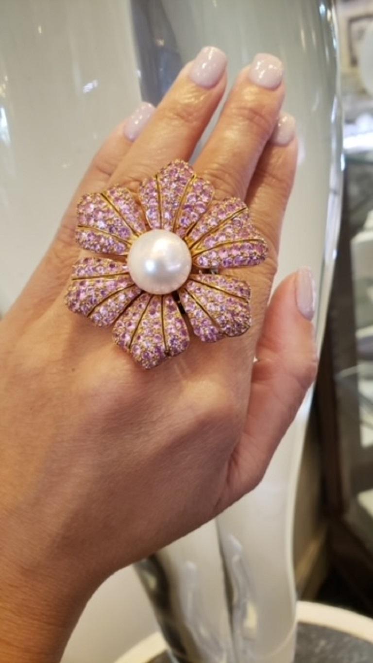 Fun and whimsical flower cocktail ring featuring a bright white South Sea pearl center surrounded by petals of pave set pink sapphires weighing a total of 3.0 carats set in 18KT yellow gold with double band in 18KT white gold which features small