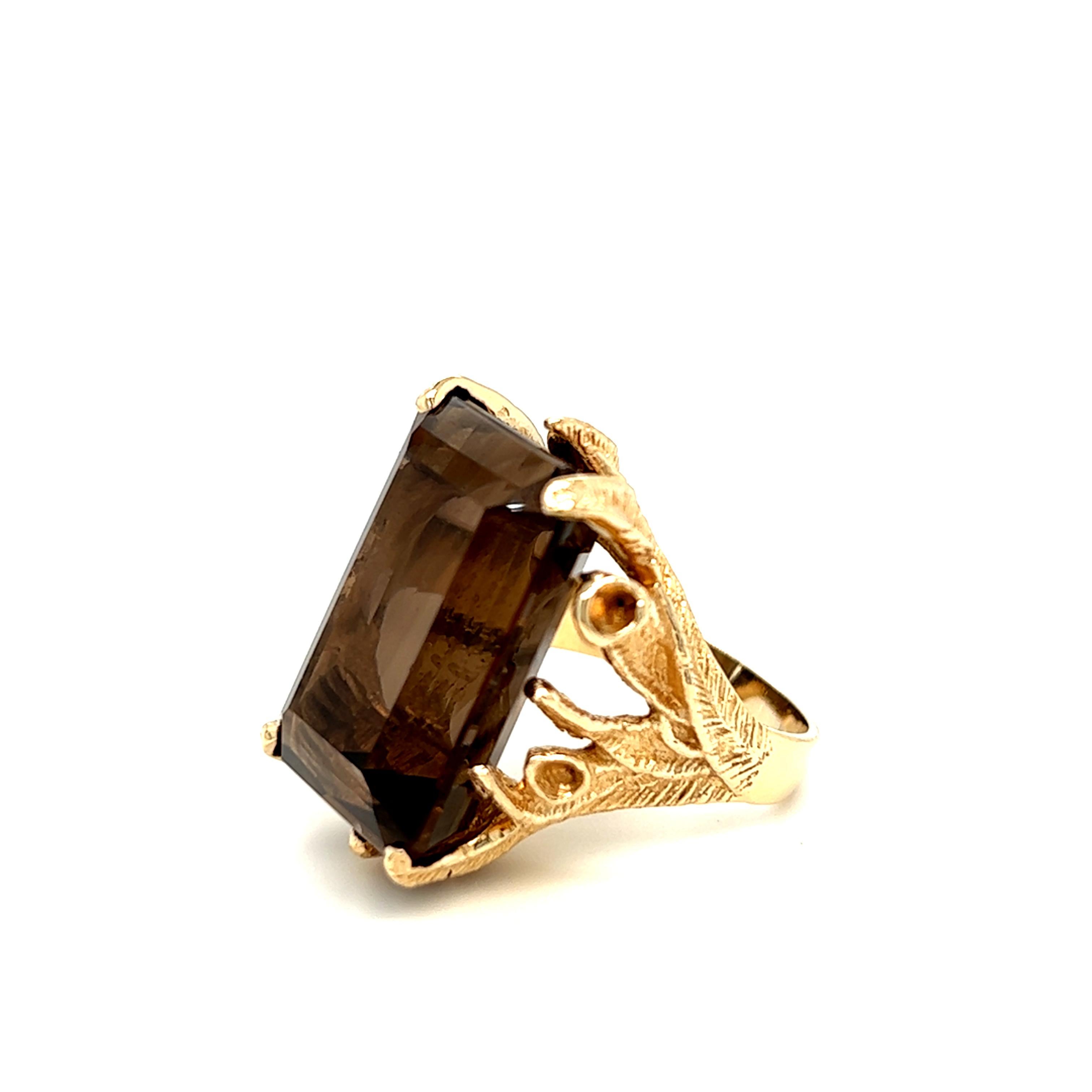 This vintage organic cocktail ring boasts a stunning 30 carat rectangular step cut smokey quartz. The center stone is set in 14k yellow gold free form branches that intertwine with three dimensional movement. The decorative prongs with foliate motif