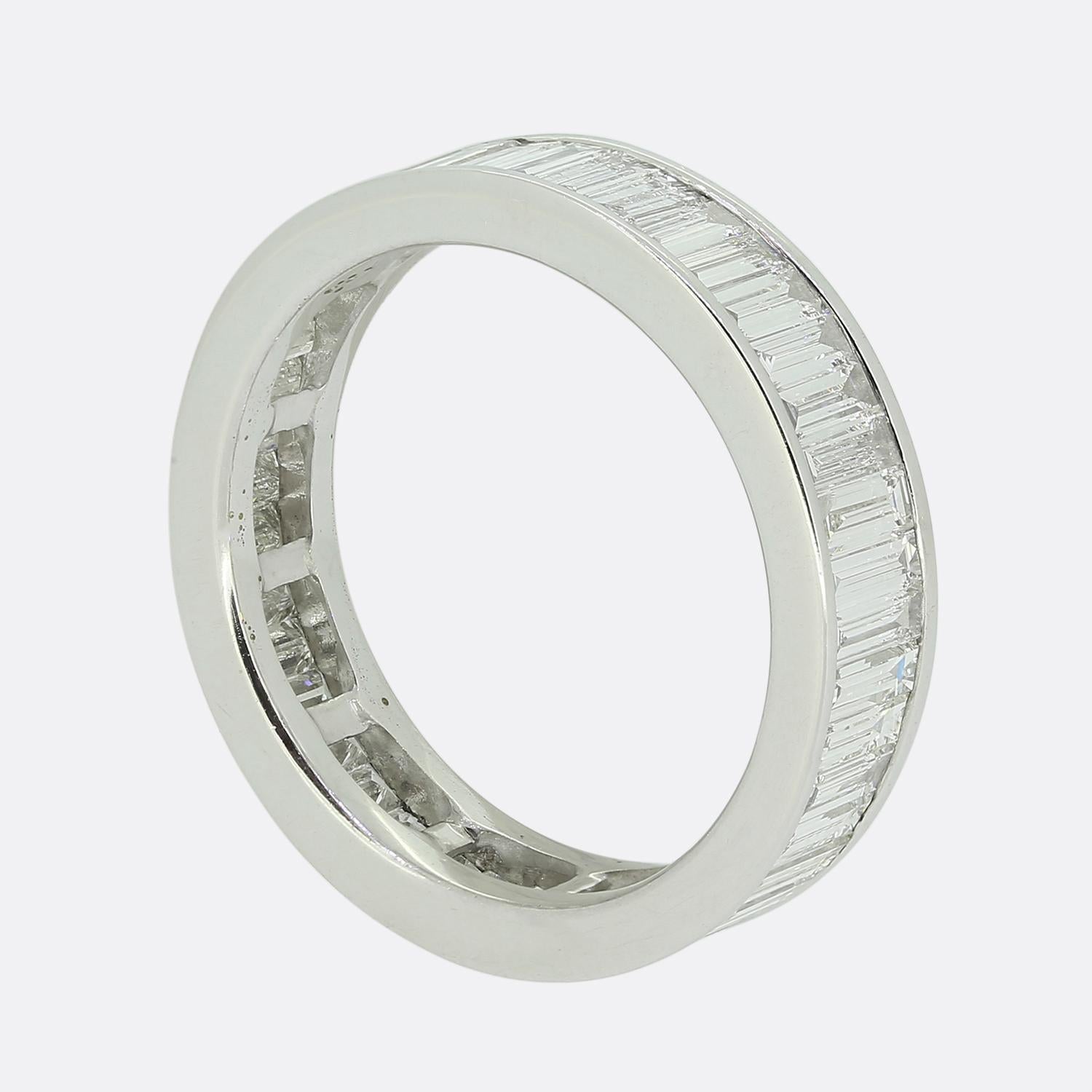 Here we have a smart and sophisticated diamond full eternity ring. This piece is meticulously crafted from 18ct white gold and features a sleek and continuous design. The band is adorned with a series of straight baguette-cut white diamonds,