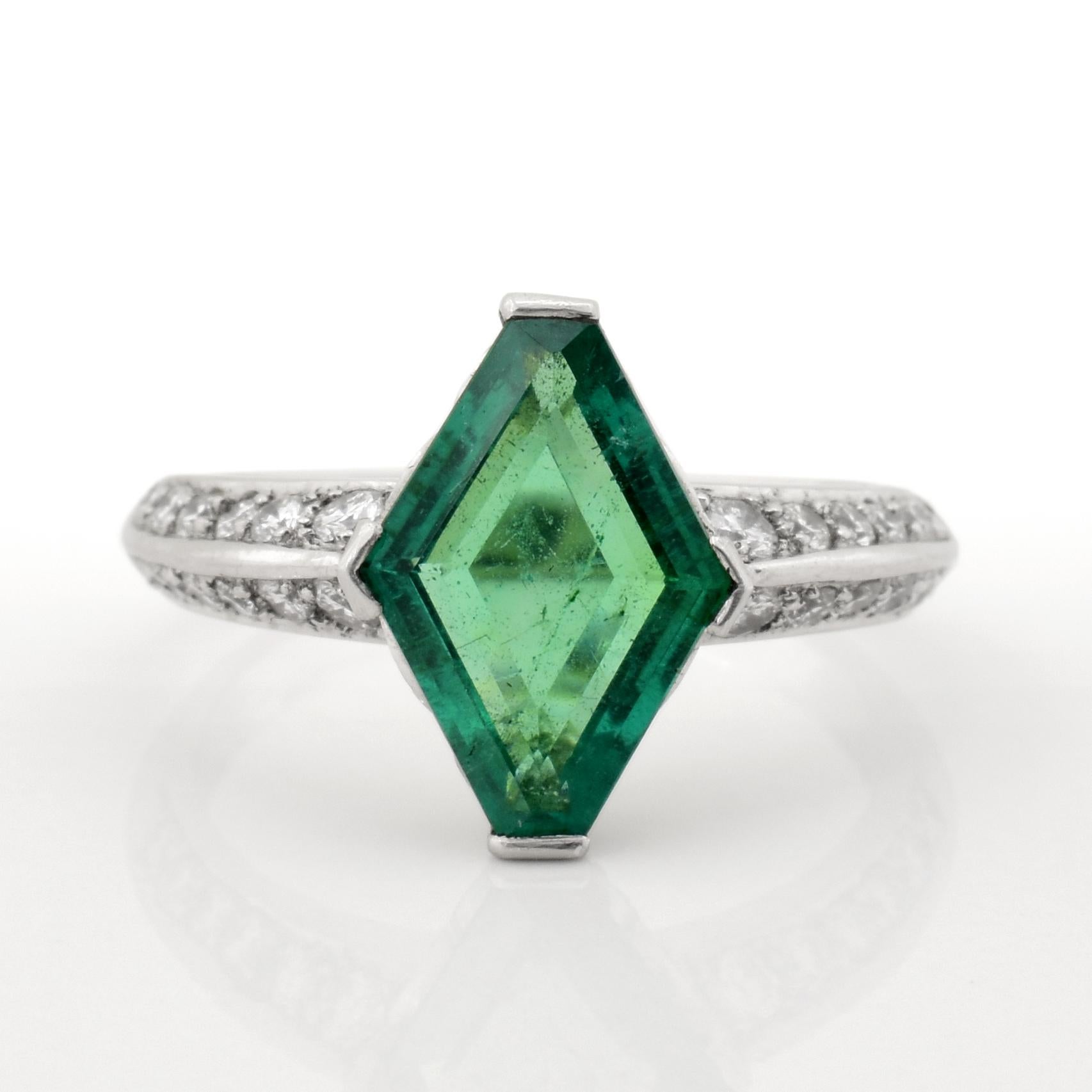 This ring is a modern piece with a deco flair. Featuring an approximately 3.00 carat lozenge cut emerald and approximately .50 carats in accent diamonds. The emerald is a light green hue that is vibrant and full of color. The ring is stamped with