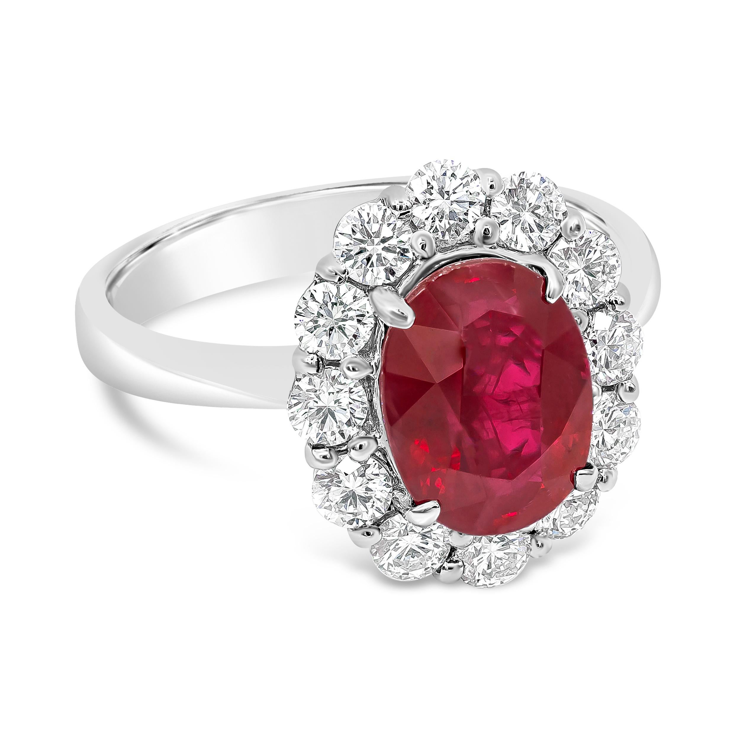A beautiful engagement ring, showcasing a 3.00 carats oval cut ruby certified by GIA as Burmese, set on a four prong setting. Accented by a halo of round brilliant cut diamonds weighing 0.89 carat total, set on a shared-prong design with a floral