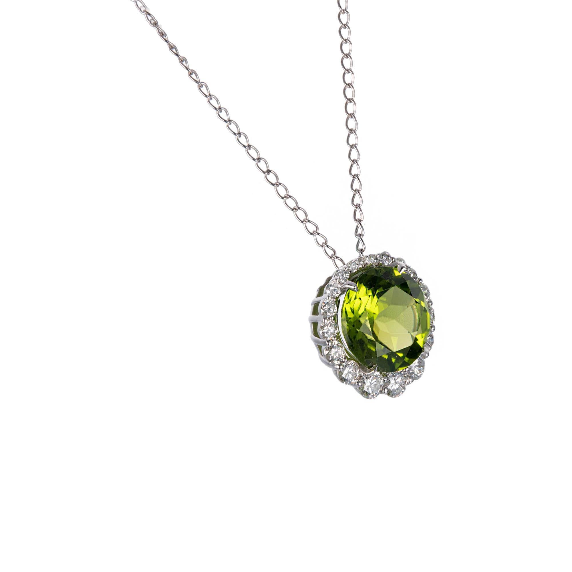 Green round Peridot pendant with a halo of white diamonds, on an 18k white gold chain. 

1 round fine green Peridot, approx. total weight 3.00cts, 10mm
18 round full cut diamonds, approx. total weight .57cts, F, VS
14k white gold
Tested and stamped: