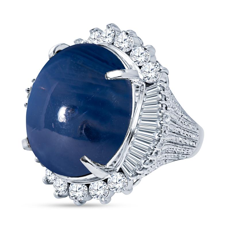 This unique and spectacular ring features a 30.00 carat natural star sapphire accented by 1.87 carat total weight in round and tapered baguette diamonds. It is set in platinum with a tapered band that has intricate beaded milgrain work. It is a size