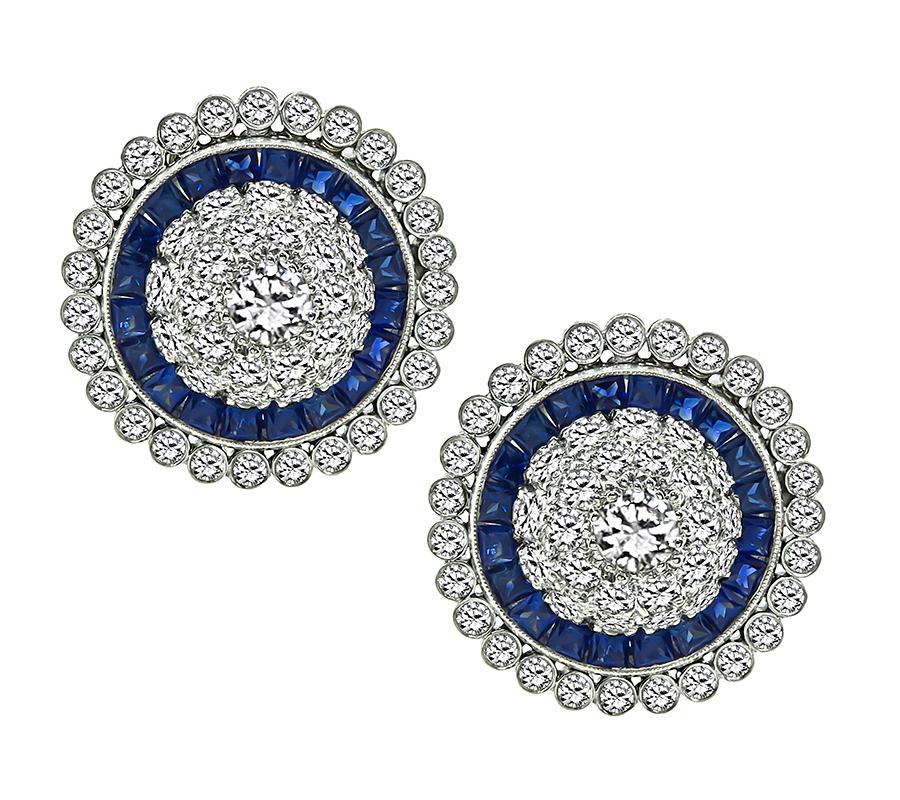 This is a fabulous pair of platinum and gold earrings. The earrings feature sparkling round cut diamonds that weigh approximately 3.00ct. The color of the diamonds is H-I with VS clarity. The diamonds are accentuated by lovely calibre cut sapphires