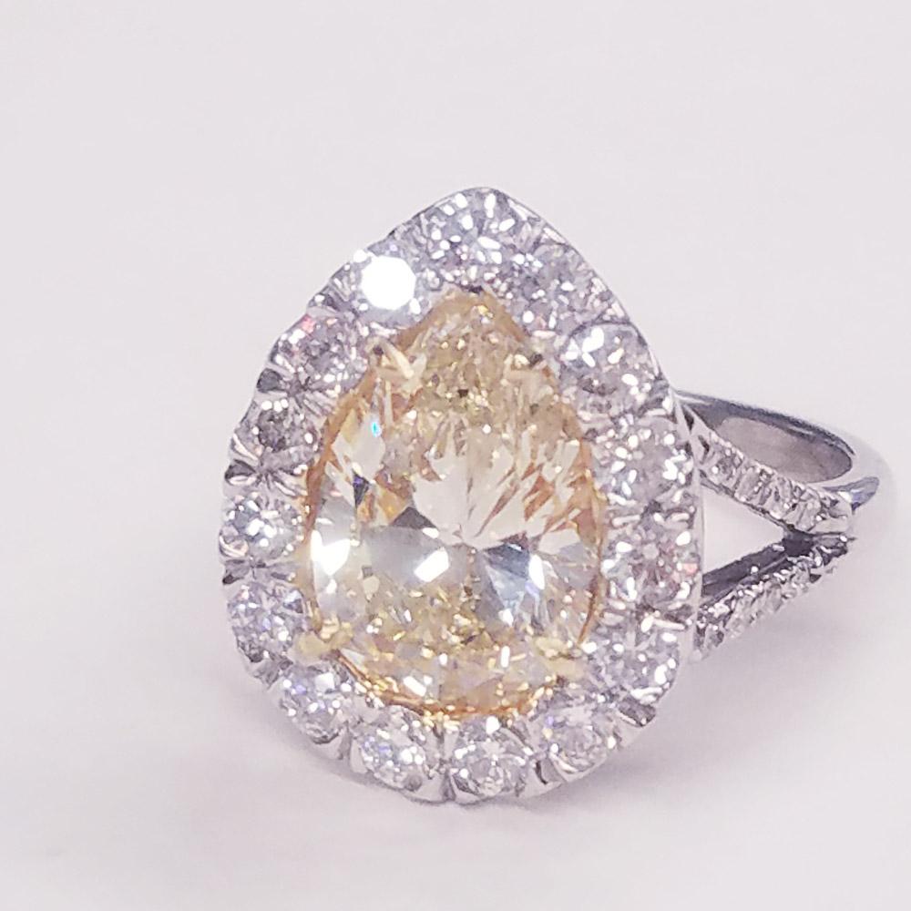 Here comes the sun. This sparkling sun kissed yellow diamond ring is a dream! The irresistible 3.01 carat VVS2 pear shape center is set ablaze surrounded by glimmering white diamonds. Diamonds dance gleefully around the center and even make their