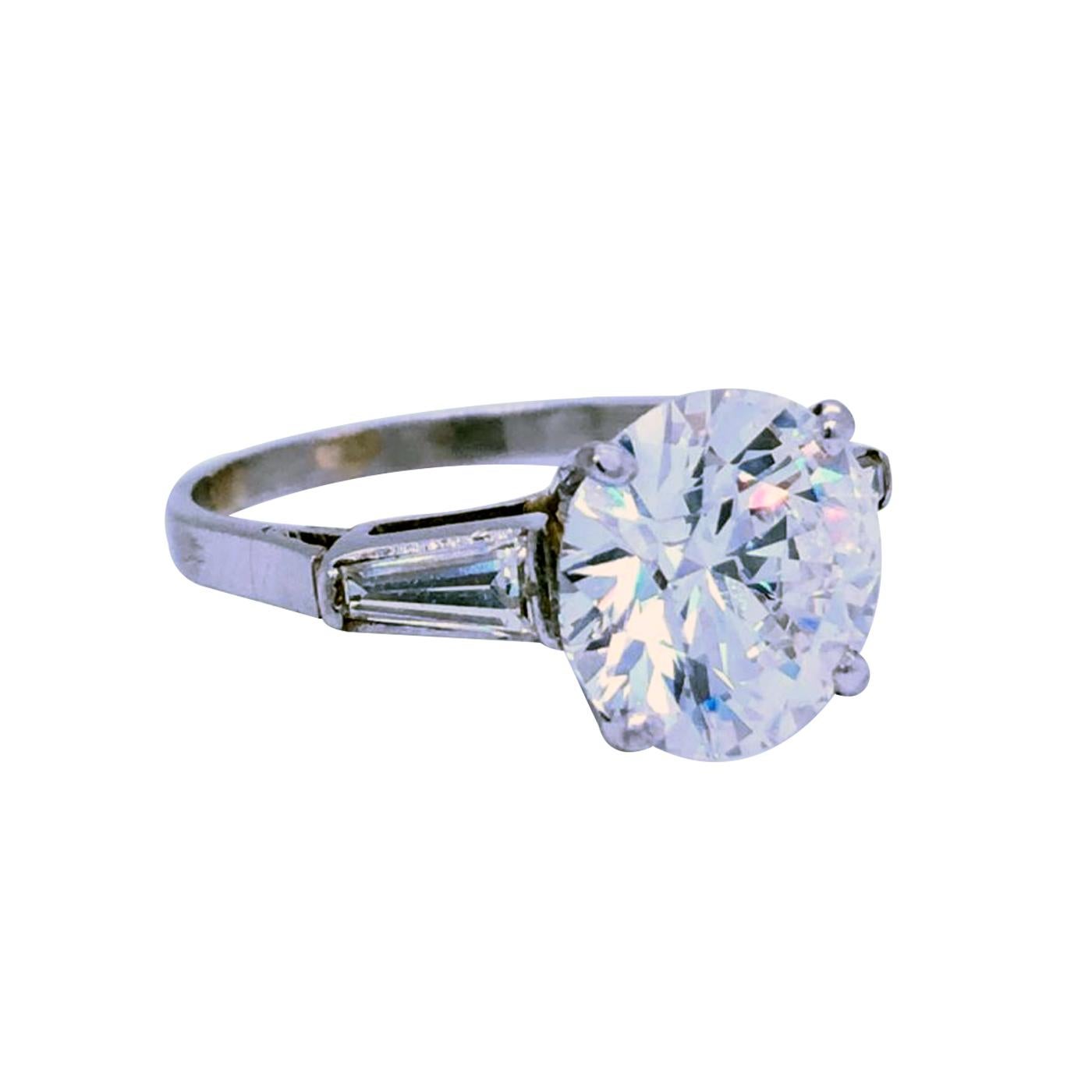 Classic Diamond ring 3.01 Carat center Round Brilliant Certified by GIA as I - Color, VS1  Clarity, and accented by tapered baguette-cut diamonds, Totaling 0.30 carat H color, VS1 - Clarity, The ring weighs 4.00 grams, and is currently size 6, with