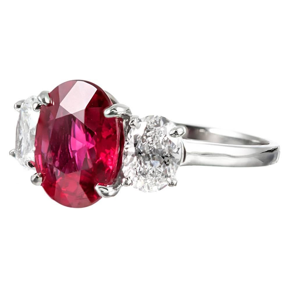 A gorgeous trio of gemstones suitable for the sophisticated collector, this 3.01 carat oval ruby sits in platinum flanked by a pair of ideally matched oval white diamonds. The accompanying GRS certificate describes the ruby as exhibiting no