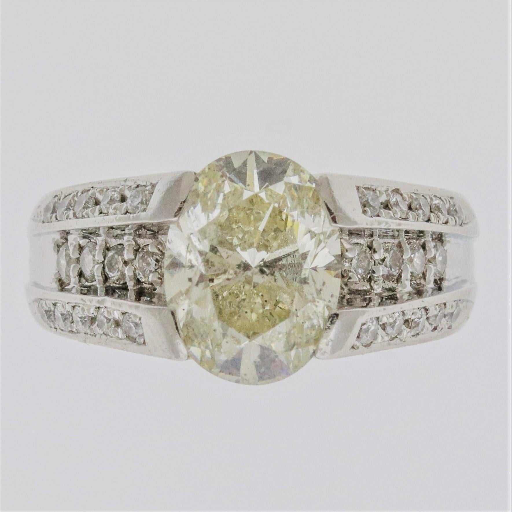 A sleek and stylish ring featuring a 3.01 carat oval shaped diamond! It has a faint yellow color with minimal eye visible inclusions. It is accented by 0.35 carats of additional diamonds set on the sides of the ring. Made in platinum, get this 3