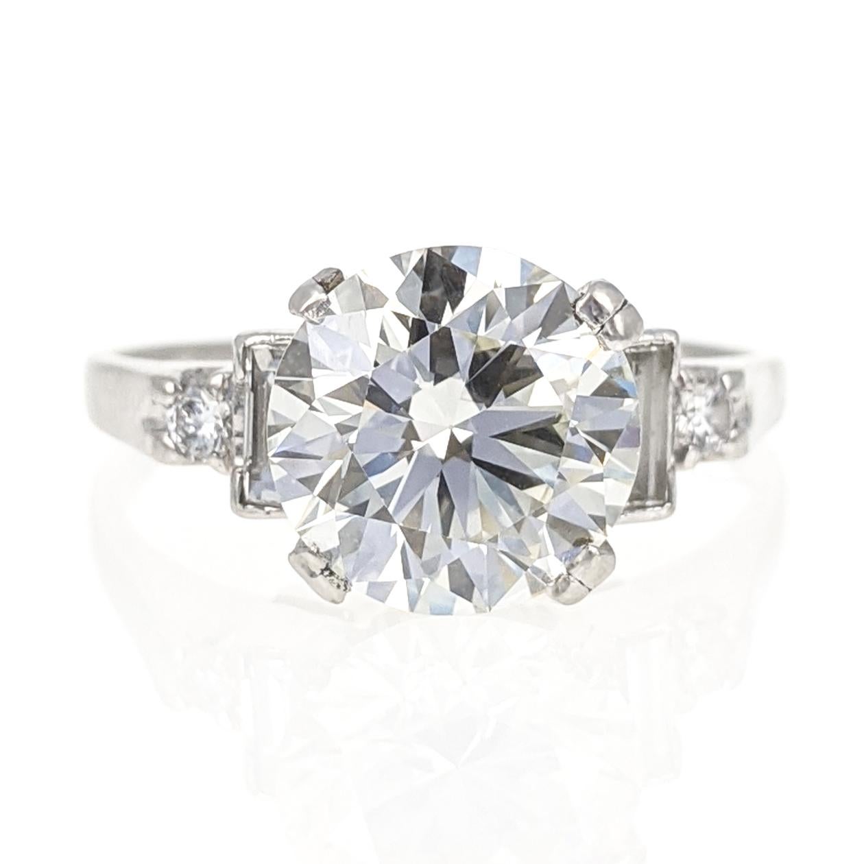 This ring centers upon a 3.02 carat round brilliant-cut diamond, flanked on each side by a baguette-cut and round brilliant-cut diamond for an additional diamond weight of approximately .22 carat. Set in platinum. Size 8.5.

With GIA report no.