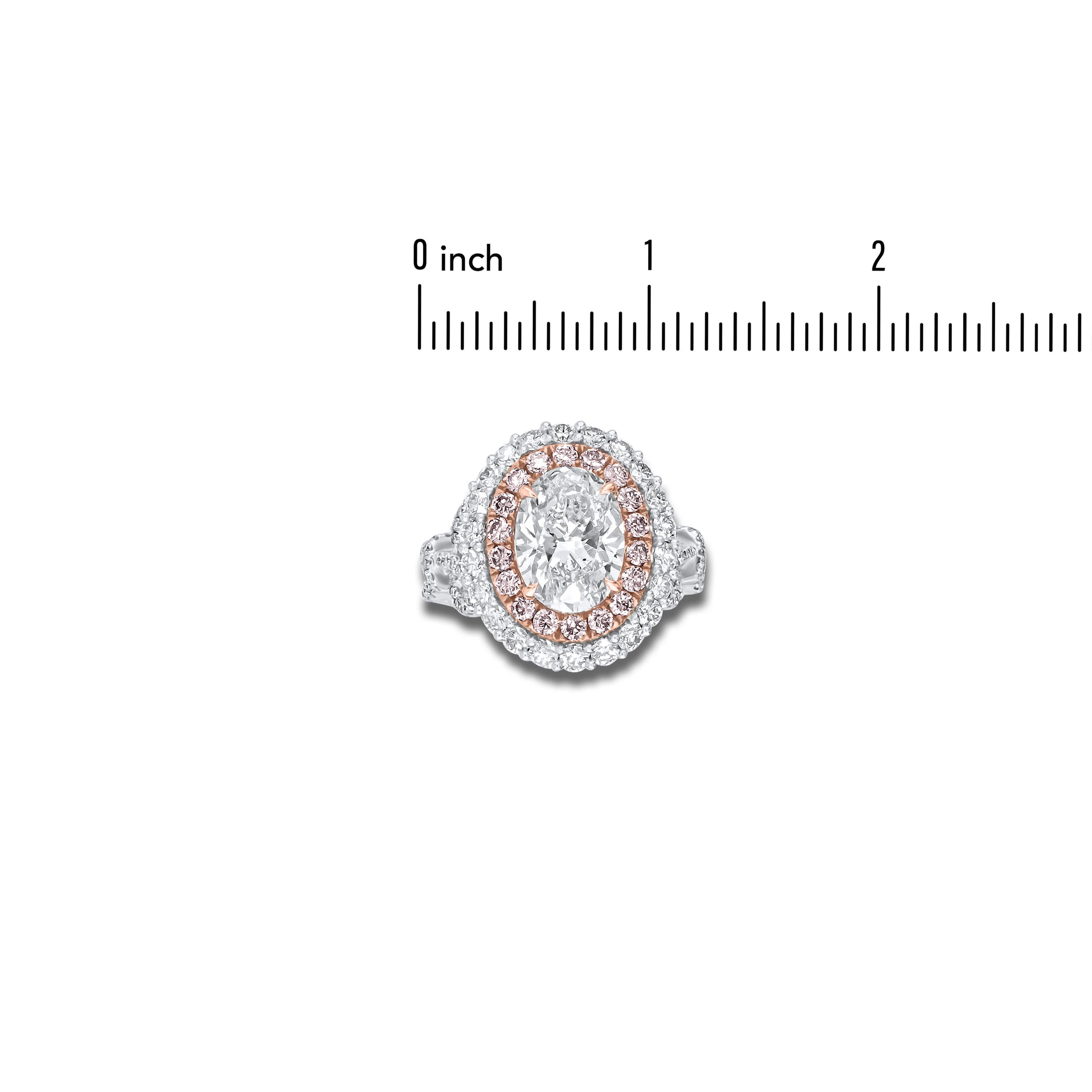 This stunning ring has a GIA-certified 3.02 carat oval diamond center, surrounded by a double halo of pink and white diamonds. Additional diamonds along the decorated shank bring the total carat weight to 5.18. The sides of the ring form a whimsical