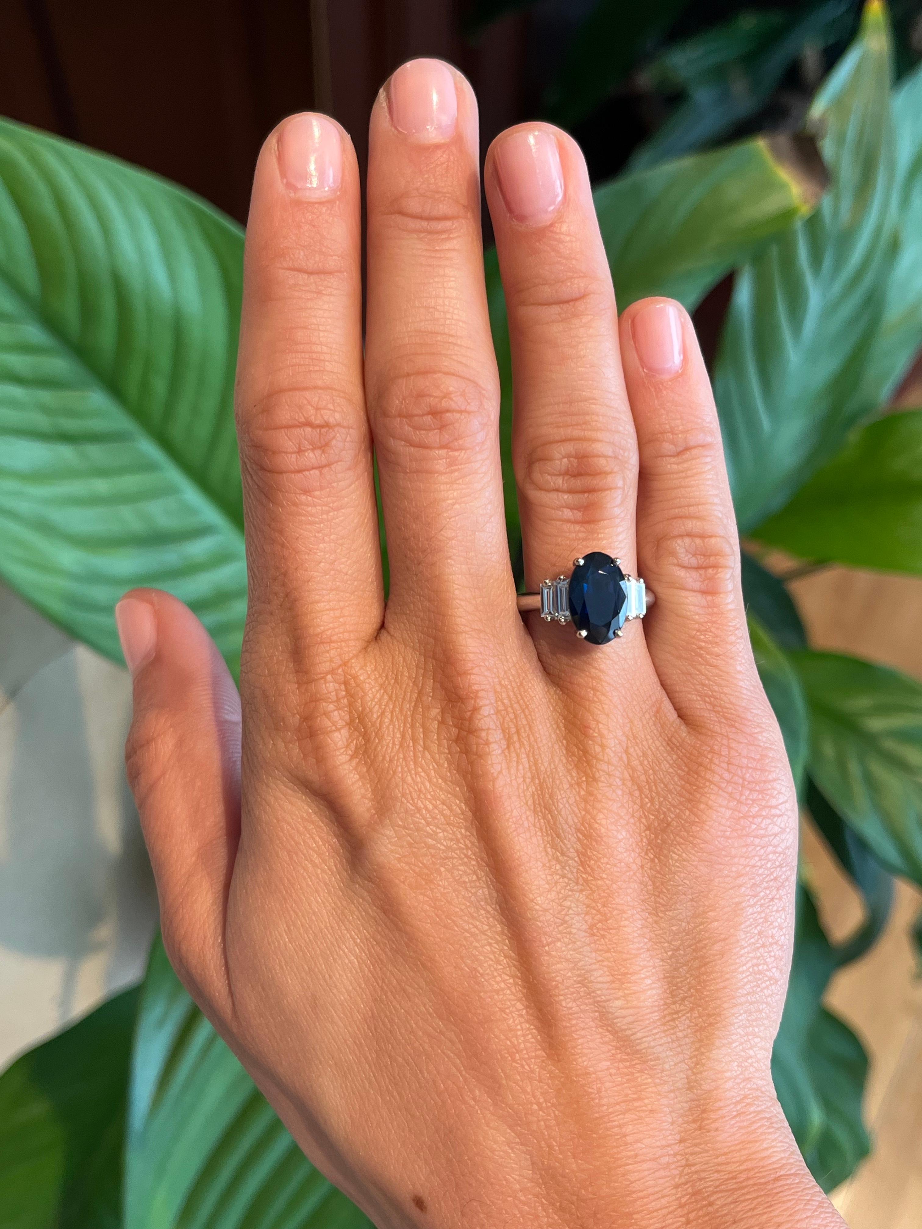 Ein schöner und großer ovaler blauer Saphir von 3,02 ct. steht im Mittelpunkt dieses Rings mit mehreren Steinen, umgeben von 0,53 ct. natürlichen Diamanten im Baguetteschliff (Reinheit VVS, Farbe G). Der Ring ist aus Platin gefertigt, was ihm ein
