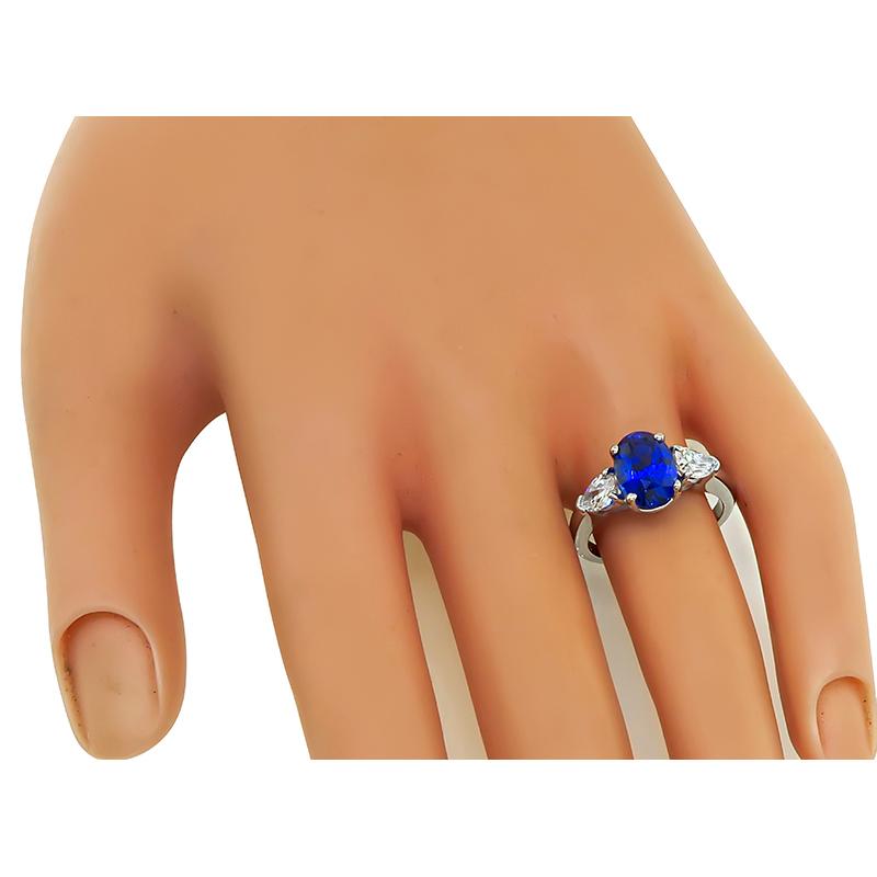 This is a gorgeous platinum engagement ring. The ring is centered with a lovely oval cut sapphire that weighs approximately 3.02ct. The sapphire is accentuated by sparkling pear shape diamonds that weigh approximately 0.80ct. The color of these