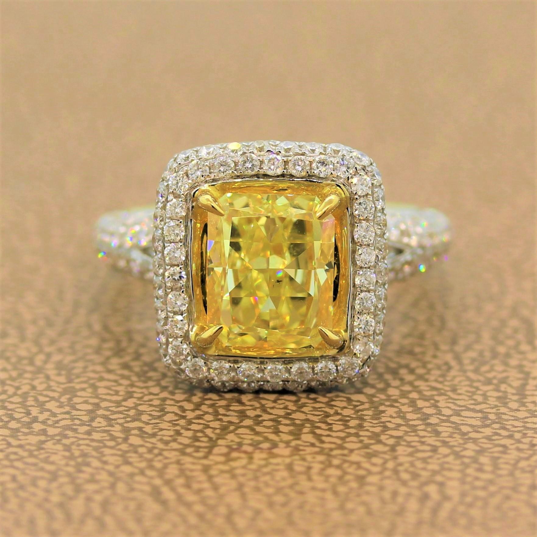 A vibrant ring featuring a 3.03 carat fancy intense yellow diamond in an 18K yellow gold setting. The cushion cut diamond is haloed by 1.52 carats of colorless diamonds. The pave set diamonds go along the split shank of this 18K white gold ring as