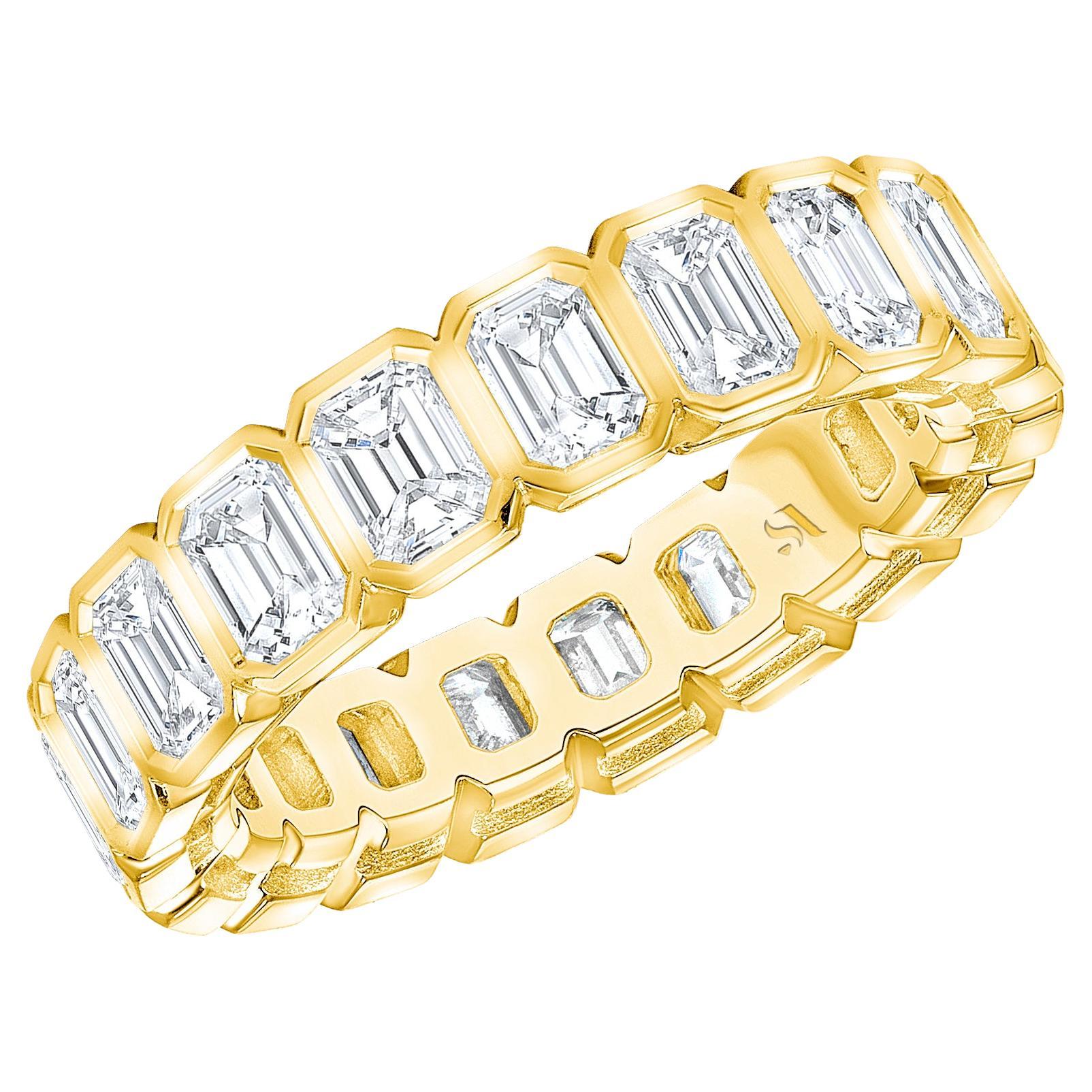 Express never-ending romance with this eternity band crafted from brightly lustrous 18k yellow gold and featuring elegantly beveled detail. It is beautifully set with emerald-cut diamonds that bring breath-taking sparkle and fire as they catch the