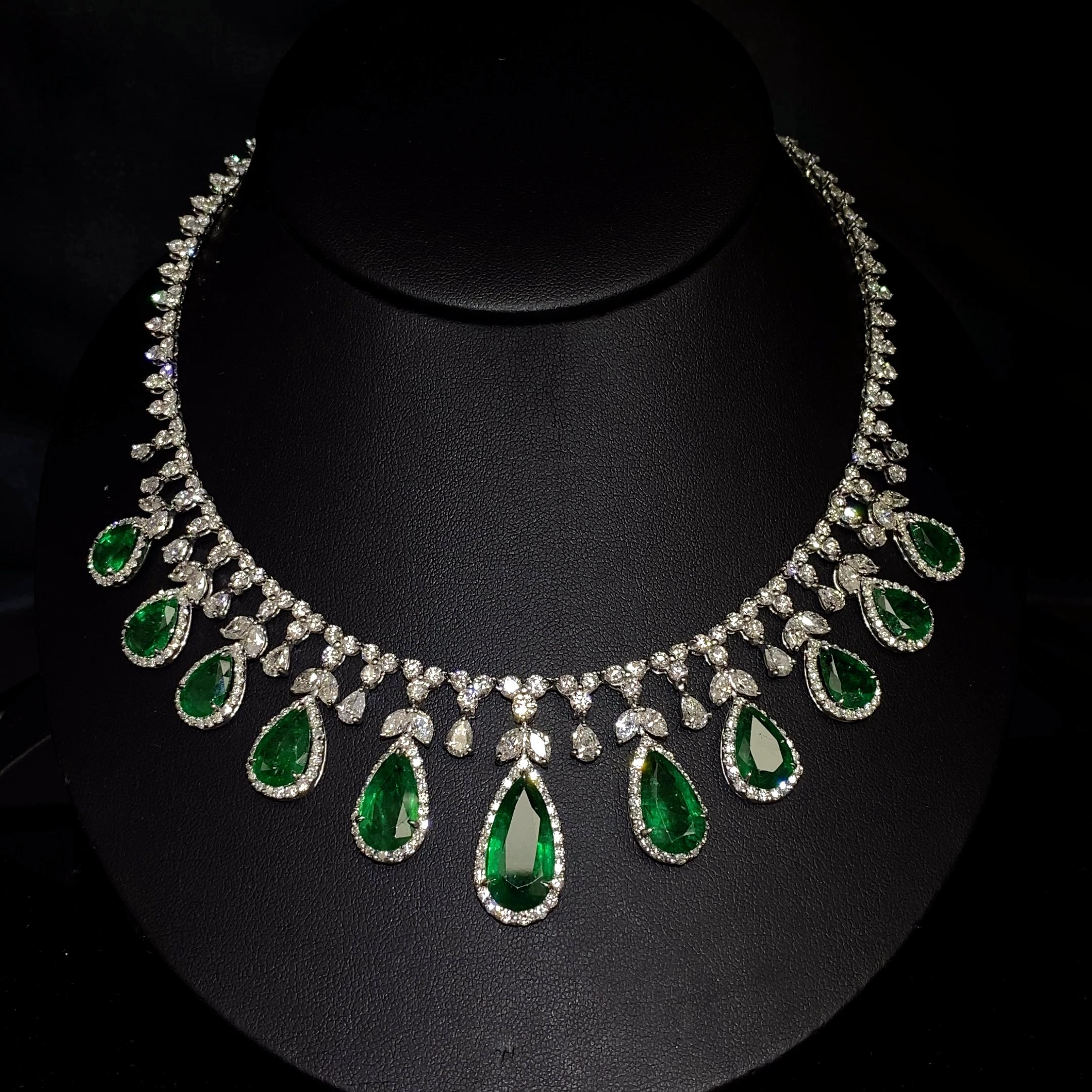 This stunning necklace features a captivating design that showcases vibrant pear-shaped green emeralds, known for their rich green hue. The piece is intricately crafted and accentuated by a combination of brilliant mixed-cut diamonds, including