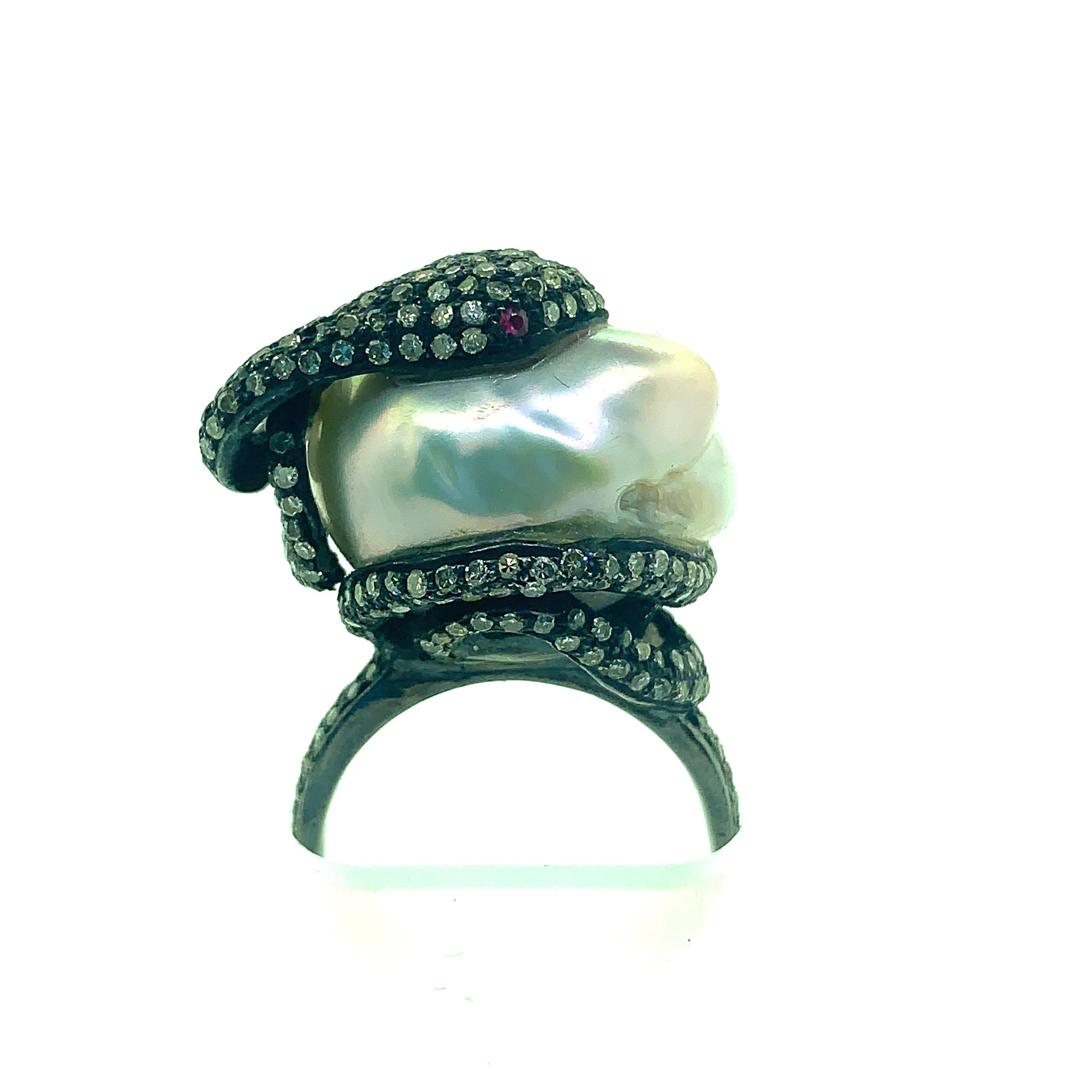 Sterling silver cocktail ring with diamond snake wrapped around a baroque south sea pearl center. Blackened oxidize sterling silver snake set with 1.79 ct champagne diamonds and 0.04 ct ruby. Pearl measure about 18mm X 16mm. This handmade ring is