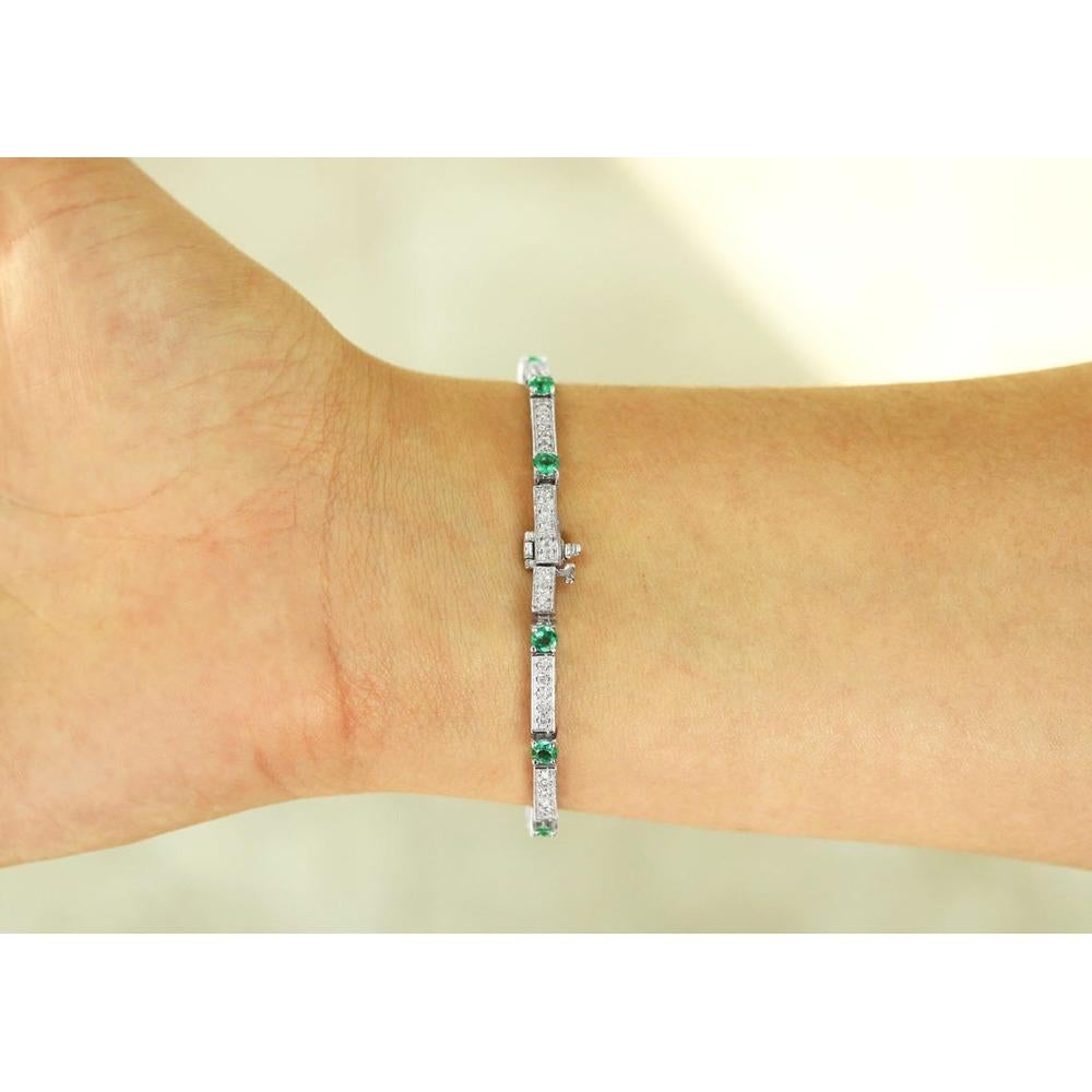 Un bracelet de tennis royal en émeraudes et diamants. Fabriquée à la main en or blanc 14K étincelant, cette pièce présente des émeraudes colombiennes rondes qui alternent avec des maillons pavés de diamants dorés. Les diamants se trouvent entre