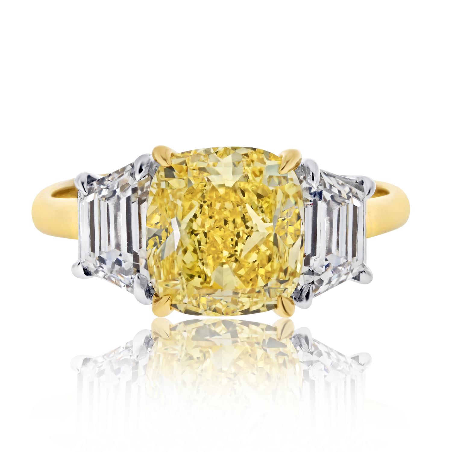 Erhöhen Sie Ihre Liebesgeschichte mit Opulenz und Anmut durch diesen außergewöhnlichen 3,03ct Fancy Vivid Yellow Cushion Cut Three Stone Diamond Engagement Ring. 

Sein Herzstück ist ein faszinierender 3,03-Karat-Diamant in Fancy Vivid Yellow,