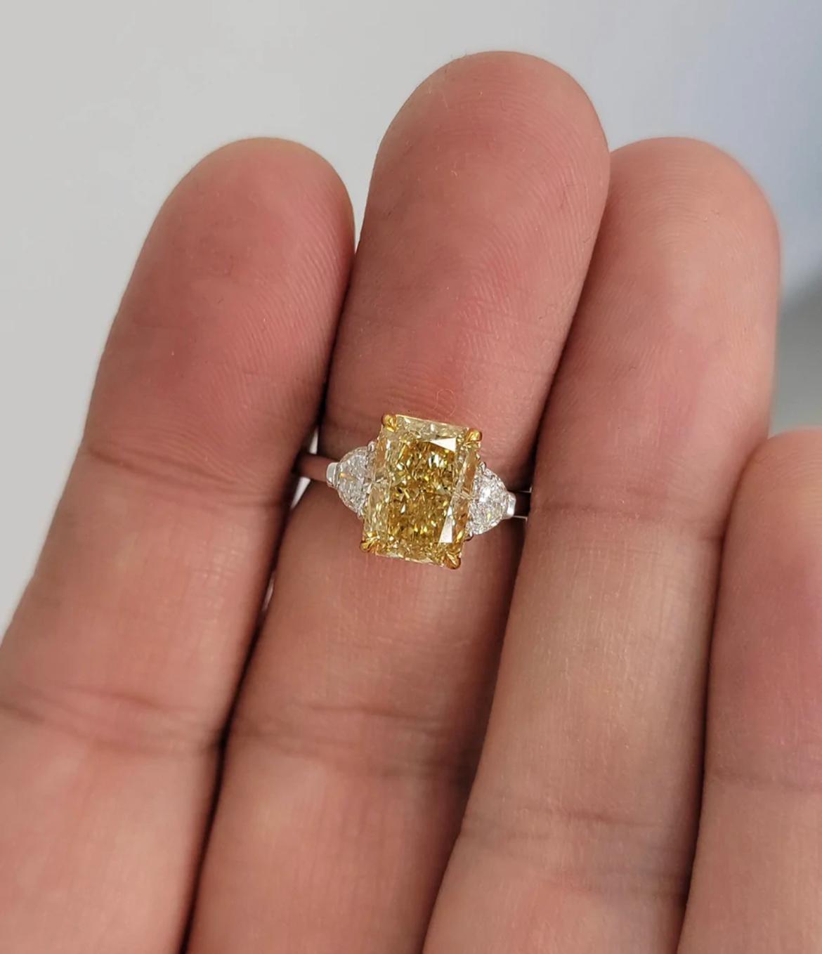-?Stunning 3ct long Radiant cut certified as Fancy Brownish Yellow 
- Saturated golden yellow color
- 1.39 Ratio
- Color very evenly spread throughout the stone
- Fiery diamond
- Set in Platinum and 18kt YG with 0.40ct total weight F VS Half Moons