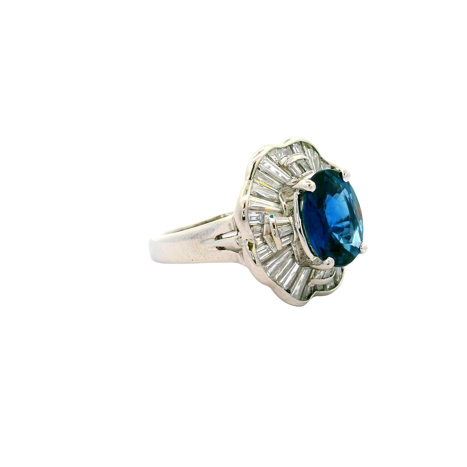 An exquisite oval-cut blue sapphire, weighing 3.05 carats, is the focal point of this contemporary ring. The sapphire's deep blue hue captivates the eye. Surrounding the sapphire are baguette-cut white diamonds, totaling 1.37 carats, which enhance