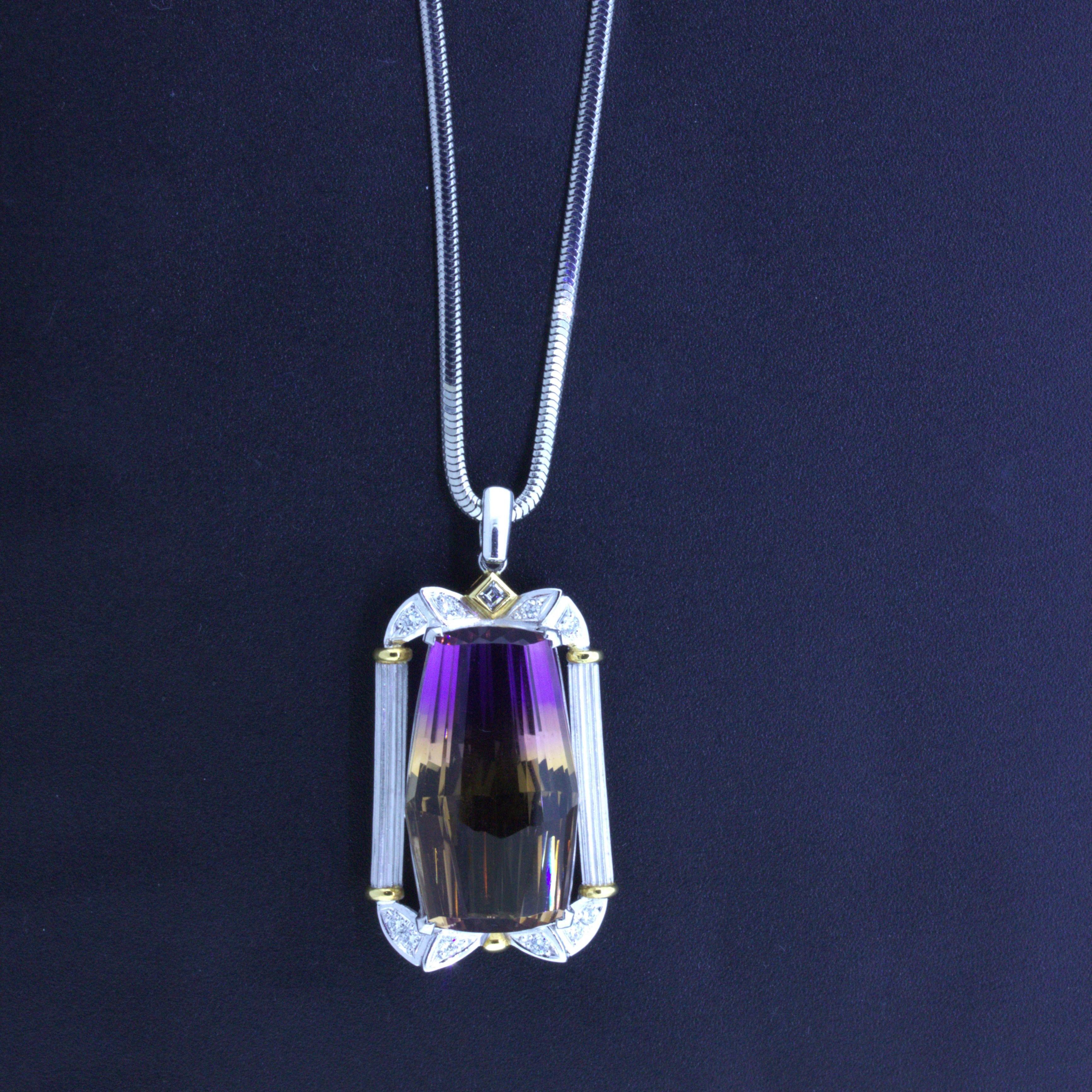 A beautiful 30.53 carat lozenge-shape ametrine takes center stage! It has a lovely orange and purple color with a sharp clean transition between the two colors. It is complemented by 0.27 carats of diamonds set around the frame of the pendant which