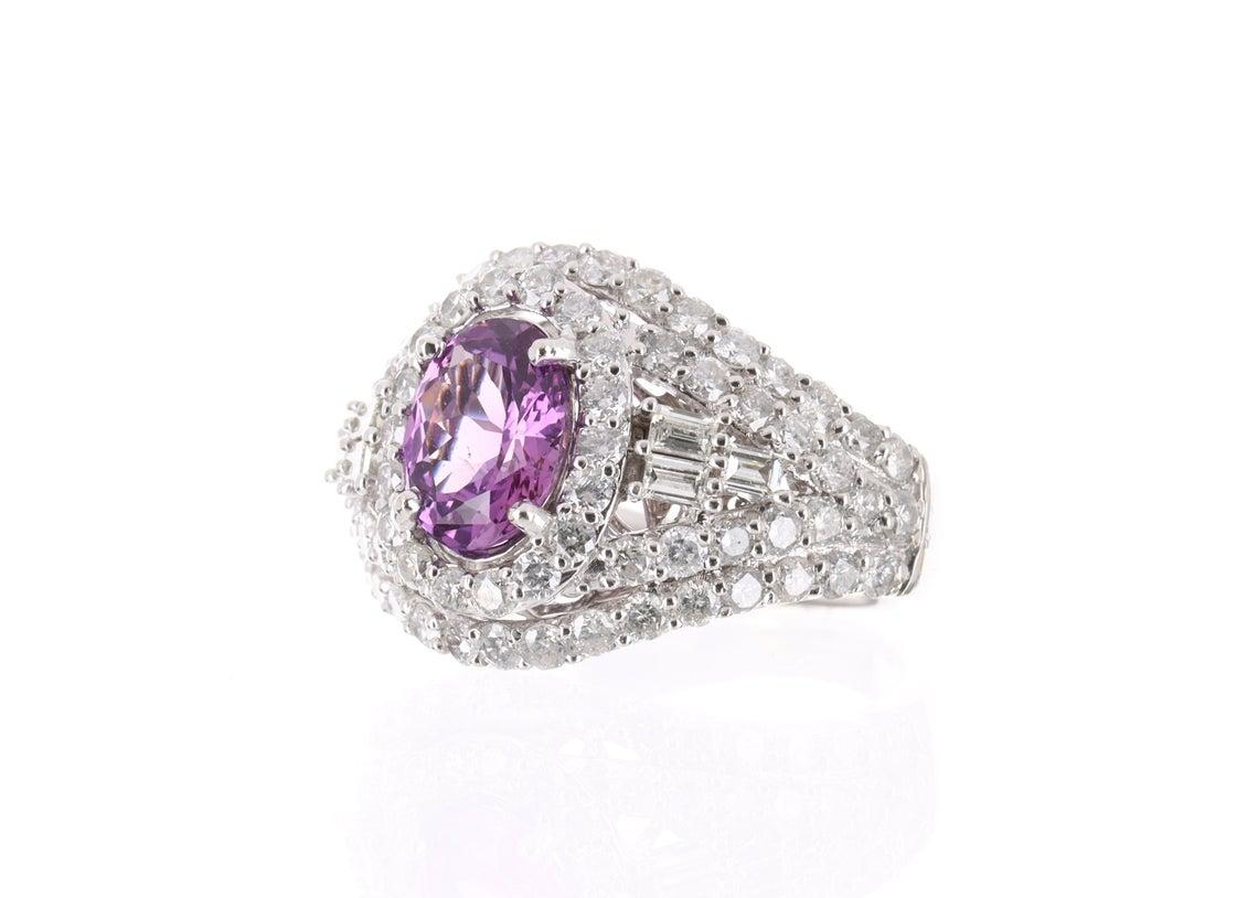 This is a custom made vivid pink, Madagascar sapphire, and diamond cluster ring. This ring features a 1.47ct natural pink sapphire. The oval cut sapphire is accented with 56 brilliant round diamonds adding up to 1.58 Carats. This handmade ring was