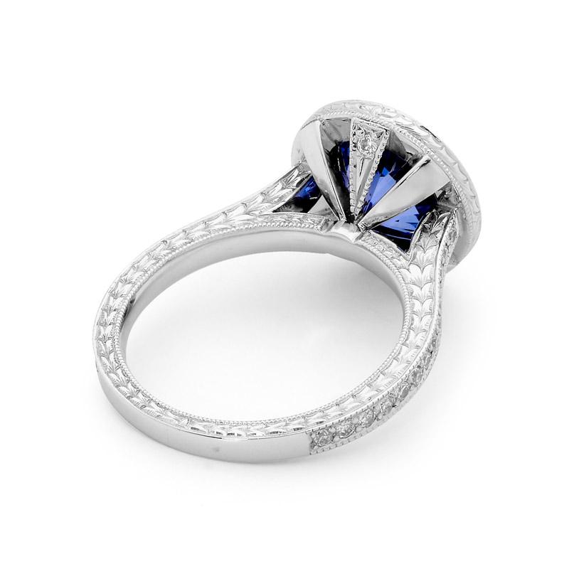 This Matthew Ely vintage style art deco inspired ring is handmade in Platinum and features an 3.07CT Ceylon Sapphire, surrounded by a halo of old cut fine white diamonds, with additional old cut diamonds on the shoulders of the band, and beautiful