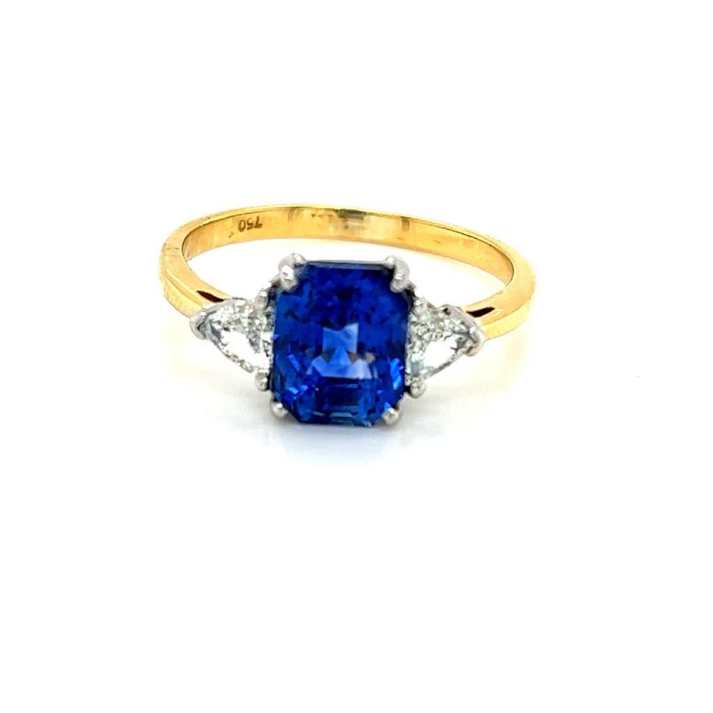 3.07 Carat Blue Sapphire and Diamond Three-Stone Ring in 18 Karat Yellow Gold

This expertly handcrafted ring features a resplendent Emerald cut Blue Sapphire with a Triangle cut Diamond on either side of it, held in a claw setting on an 18K Yellow