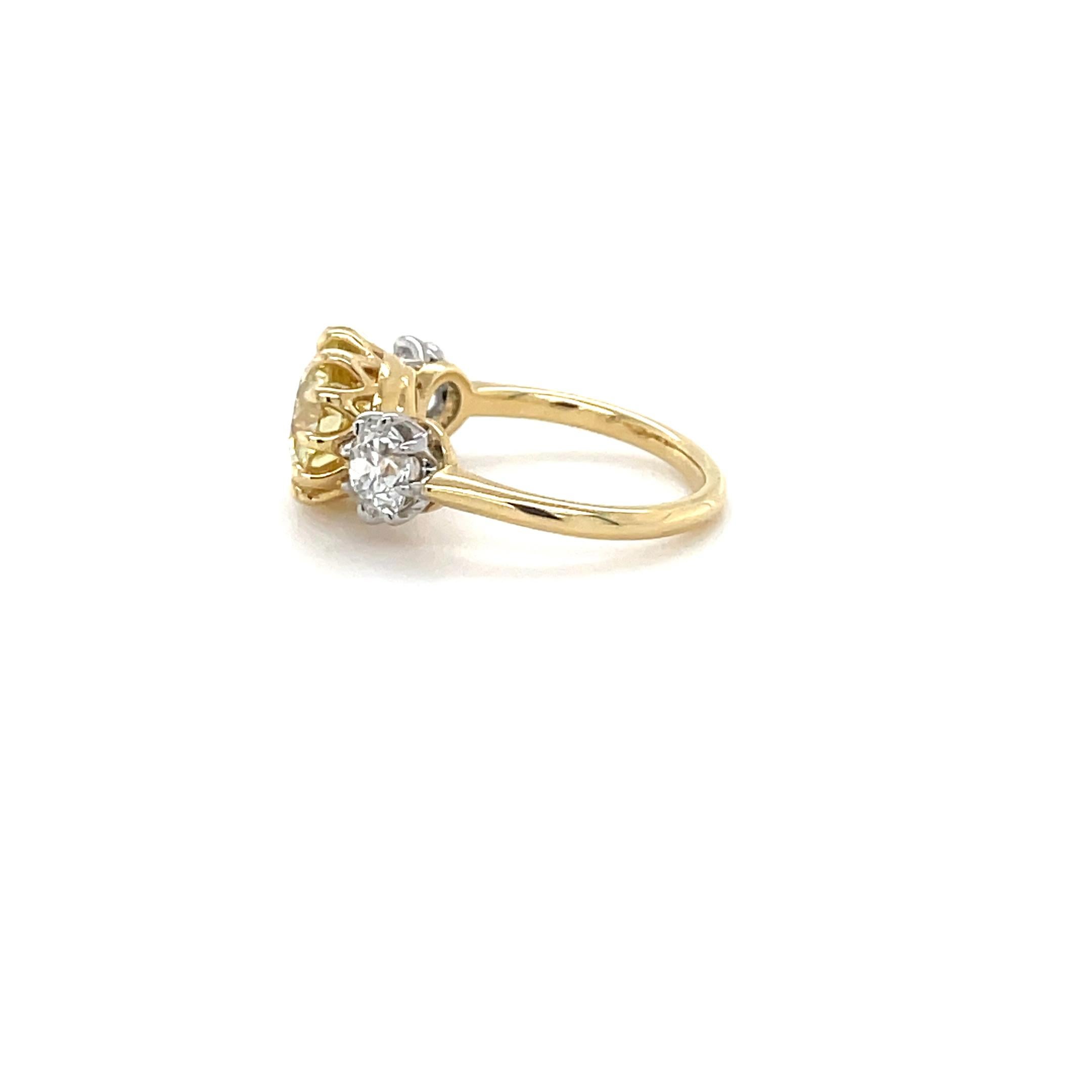 This unique Victorian style three stone diamond ring boasts a 3.08 carat Natural Fancy Yellow cushion cut diamond surrounded by beautiful claw prongs and flanked by two old European cut diamonds mounted in platinum and weighing 1.22 carats total.