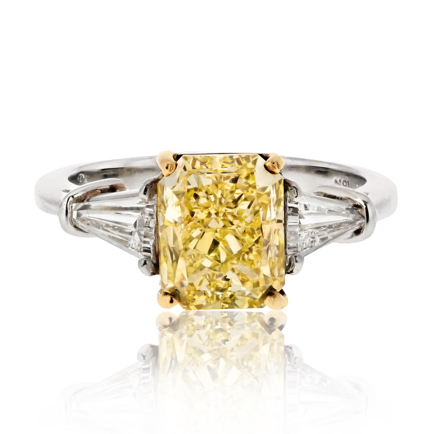 Embrace the extraordinary with this exquisite 3.08-carat Radiant Cut Diamond engagement ring—a dazzling celebration of love and brilliance. 

The center stage features a show-stopping Fancy Yellow diamond, certified by GIA with a remarkable VVS2