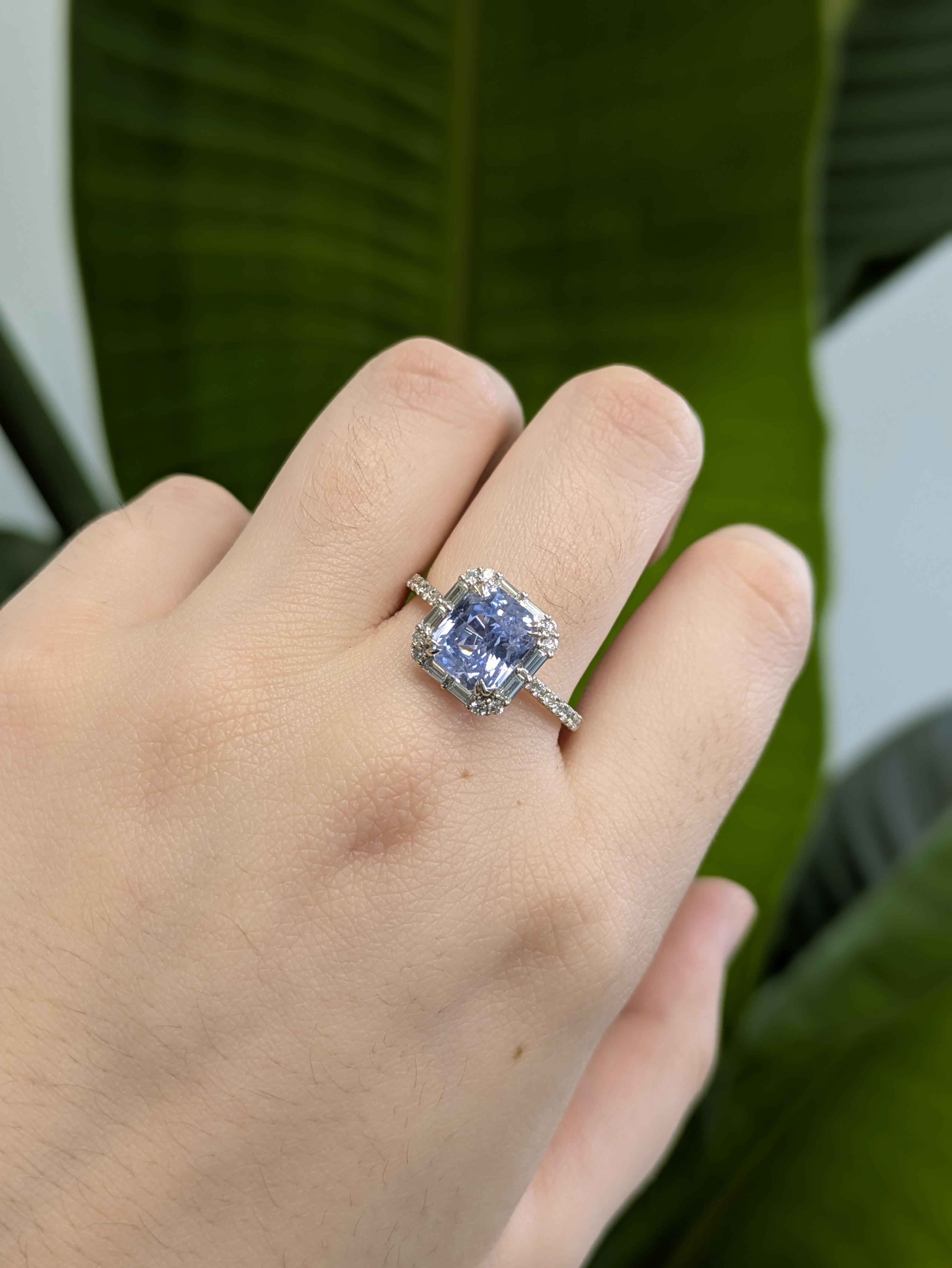 Questo elegante anello mette in mostra uno zaffiro blu fiordaliso dal taglio smeraldo di 3,09 carati (8,5x7,3 mm) in un'incastonatura sicura a doppia foratura. Circondato da una scintillante aureola di diamanti, il centro è ulteriormente arricchito