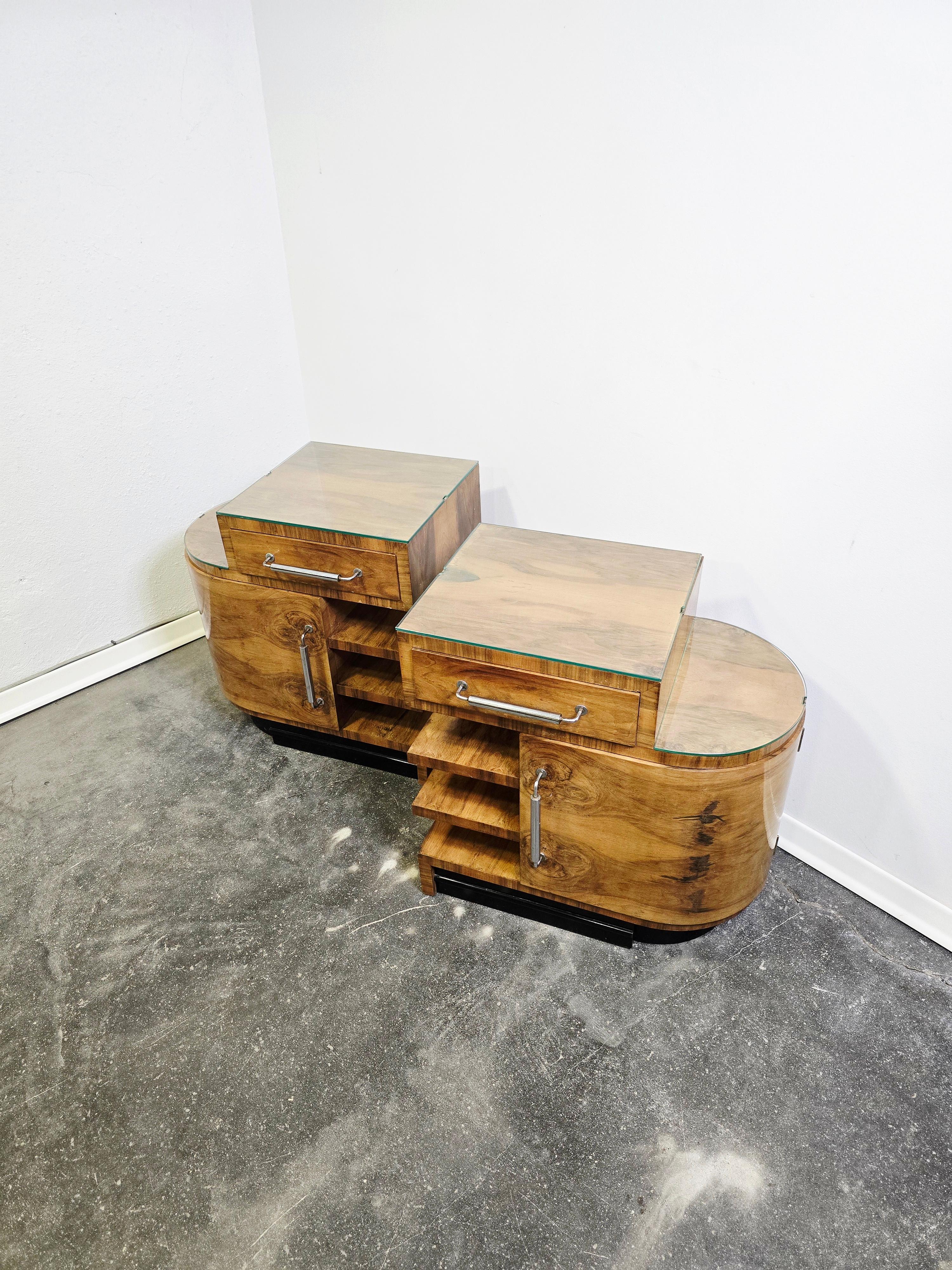 Les tables de nuit s'inspirent des caractéristiques classiques de l'Art déco : lignes géométriques épurées, symétrie, luxe subtil des matériaux et des finitions. Le placage de noyer chaud (ou le noyer massif) présente un grain riche, souvent assorti