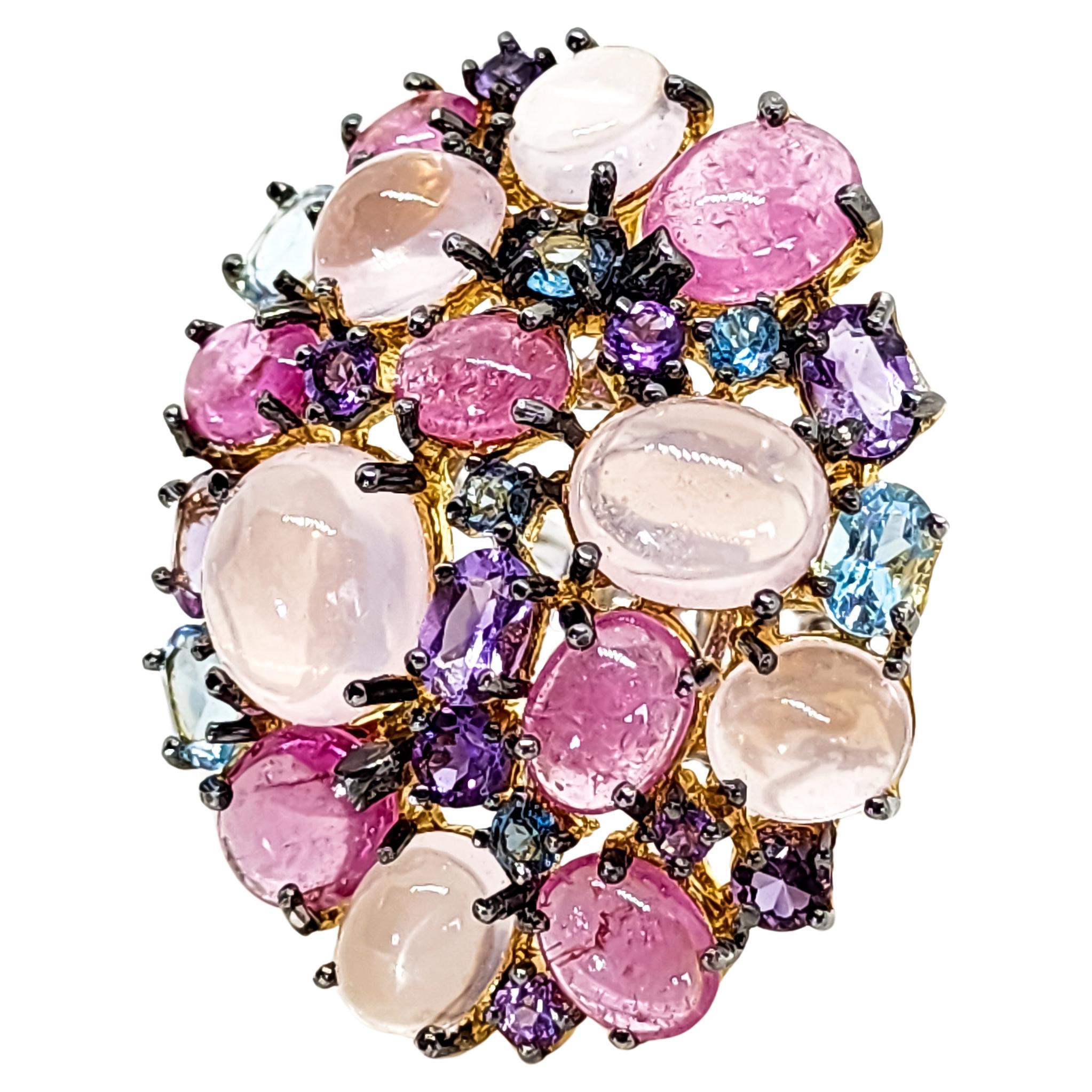 Une grande bague cocktail, en forme de grappe, présentant une confiserie délicieusement sucrée de pierres précieuses colorées dans les tons rose, bleu et violet. Cette bague festive est un accent approprié à porter en toute saison.  La grande face