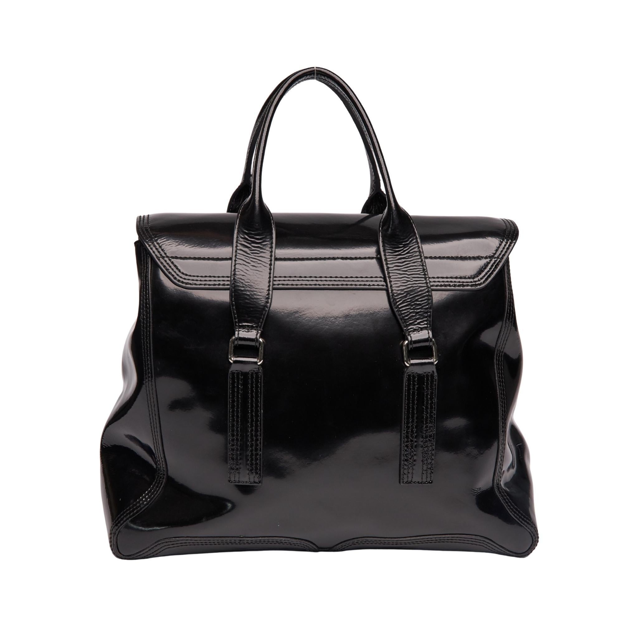 Diese Handtasche ist aus schillerndem schwarzem Lackleder gefertigt. Die Tasche verfügt über zwei flache Lederhenkel mit silbernen Gliedern, vertikale Reißverschlussfalten, Seitenwände aus schwarzem Leder und eine überkreuzte Klappe mit silbernem