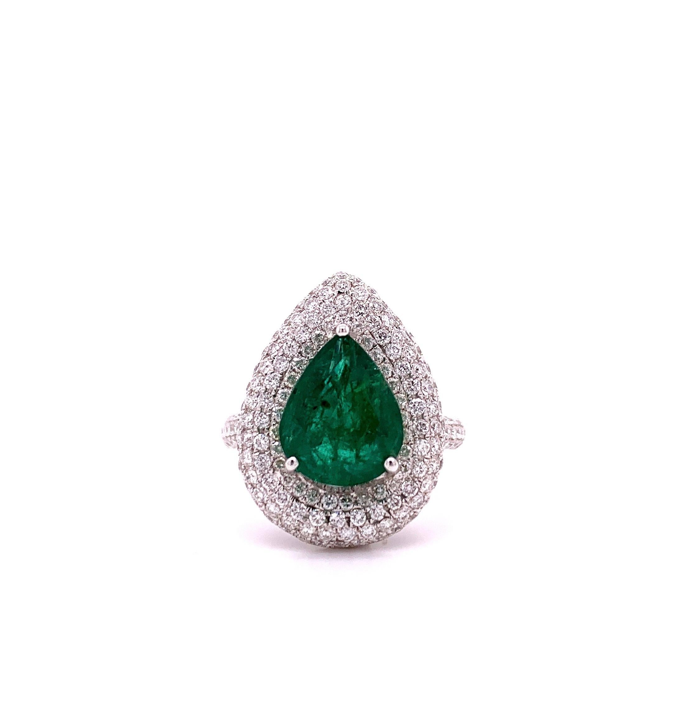 Stunning emerald diamond cocktail ring. Lively intense green with lustre, pear faceted, 3.19 carats natural emerald encased in open basket mount with three bead prongs, framed with a round brilliant cut diamond cluster, along with diamond cluster on