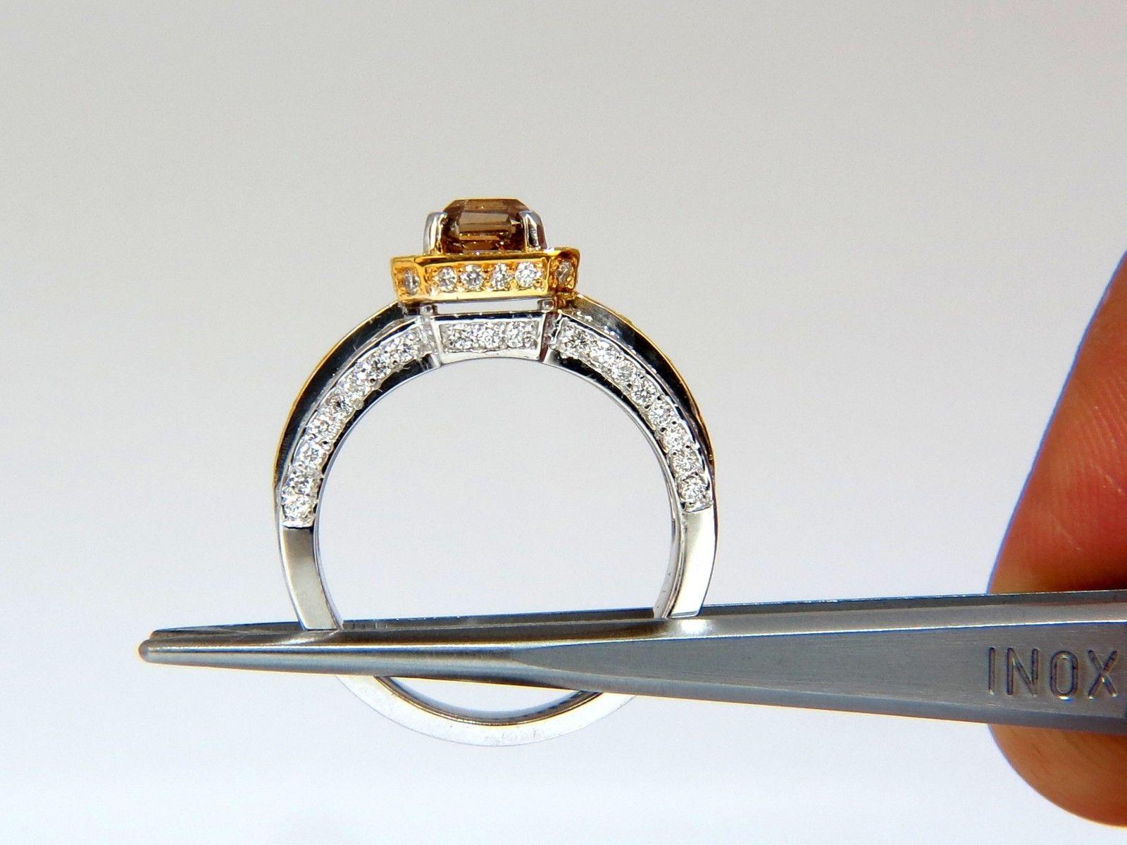 Aureola bicolor en relieve de color fantasía.

1,60 ct. diamante talla esmeralda color natural amarillo fantasía marrón

Claridad Vs-2.

5,8 X 5,1 mm

Diamantes redondos laterales de 1,50 ct.

Color G frente a claridad 2.

Oro blanco y amarillo de