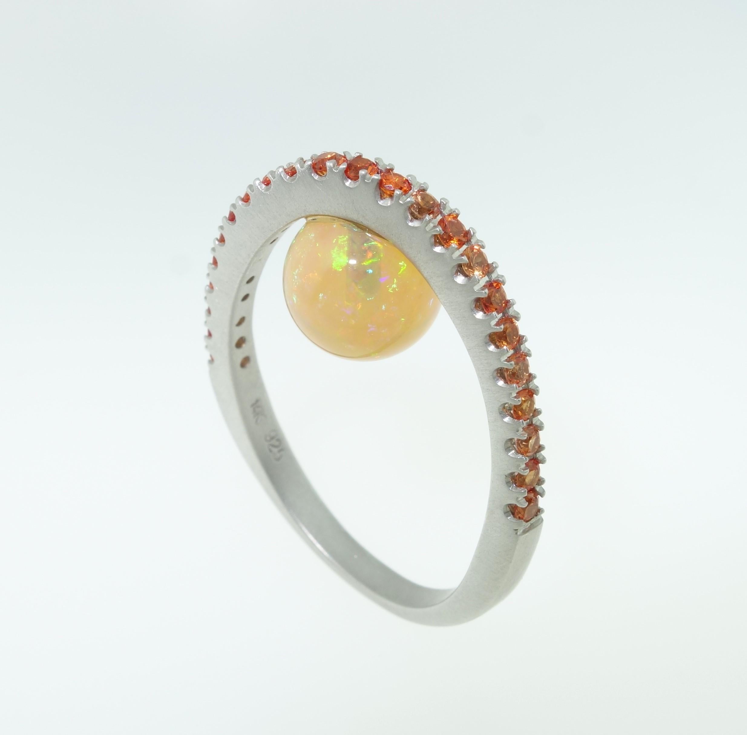 Oberer Teil des Rings mit orangefarbenen Saphiren besetzt, darunter ein äthiopischer Opal von 3,10 Karat; orangefarbene Saphire von ca. 0,70ctw; anlaufgeschützte Rhodiumfassung aus Sterlingsilber. Ringgröße 7, wir bieten Ringgrößenanpassung an. In