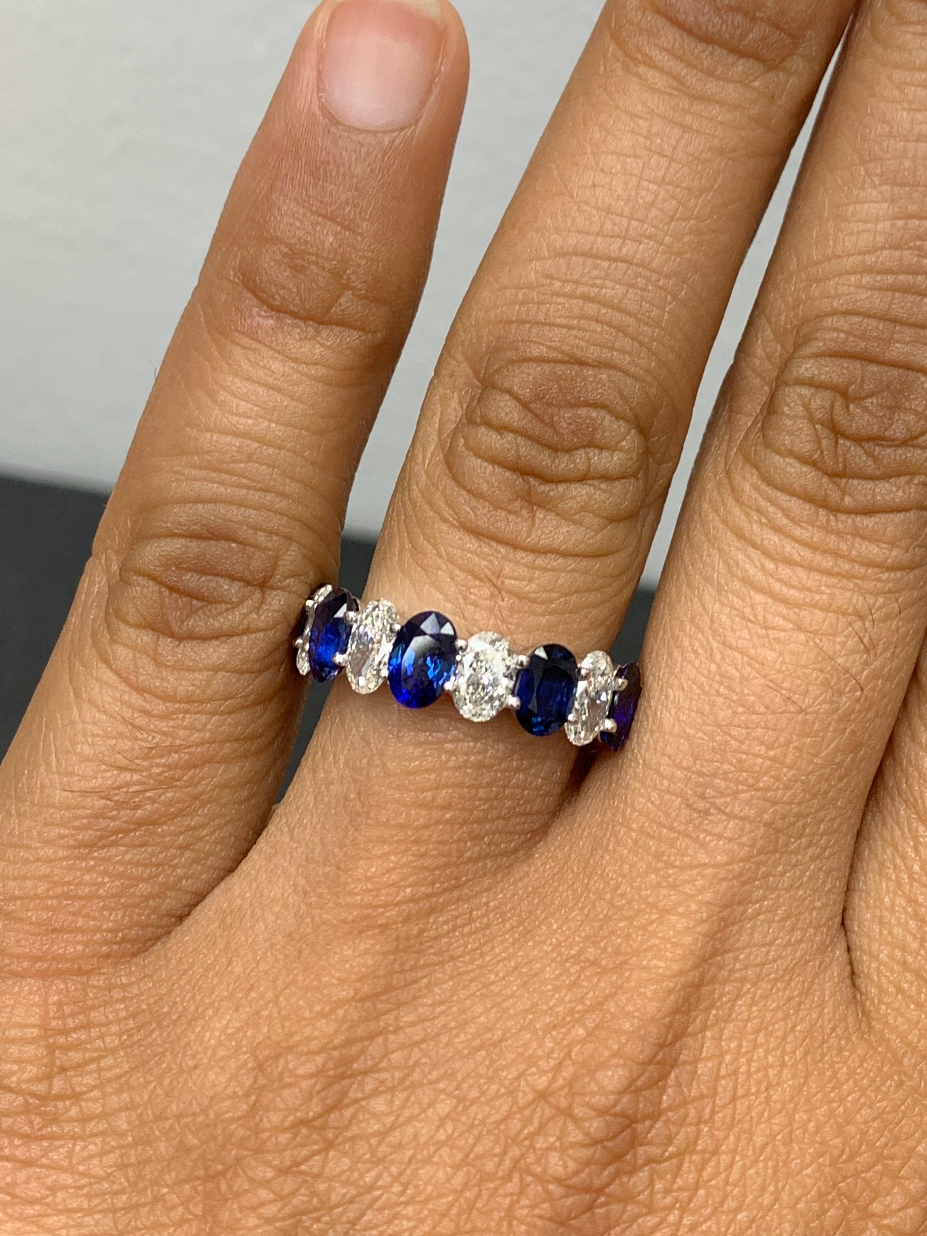 A fascinating gemstone wedding band 9 stone style showcasing 5  oval cut royal blue sapphires weighing 3.10 carats total, alternating to these blue sapphires are 4 oval cut brilliant colorless diamonds weighing 1.26 carats, Made in 14K White Gold,