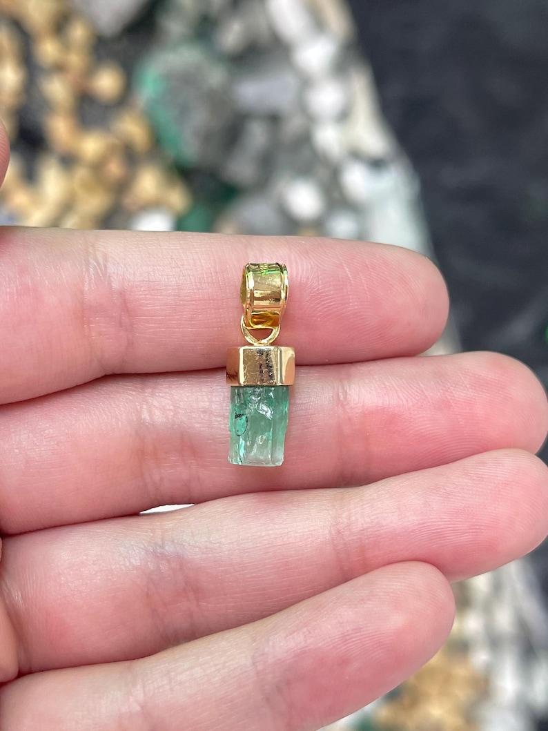 Nous vous présentons notre pendentif en émeraude brute naturelle, une pièce distinctive et unisexe mettant en valeur la beauté brute d'un cristal d'émeraude terminé de 3.11 carat provenant des paysages verdoyants de la Colombie. Le cristal brut et