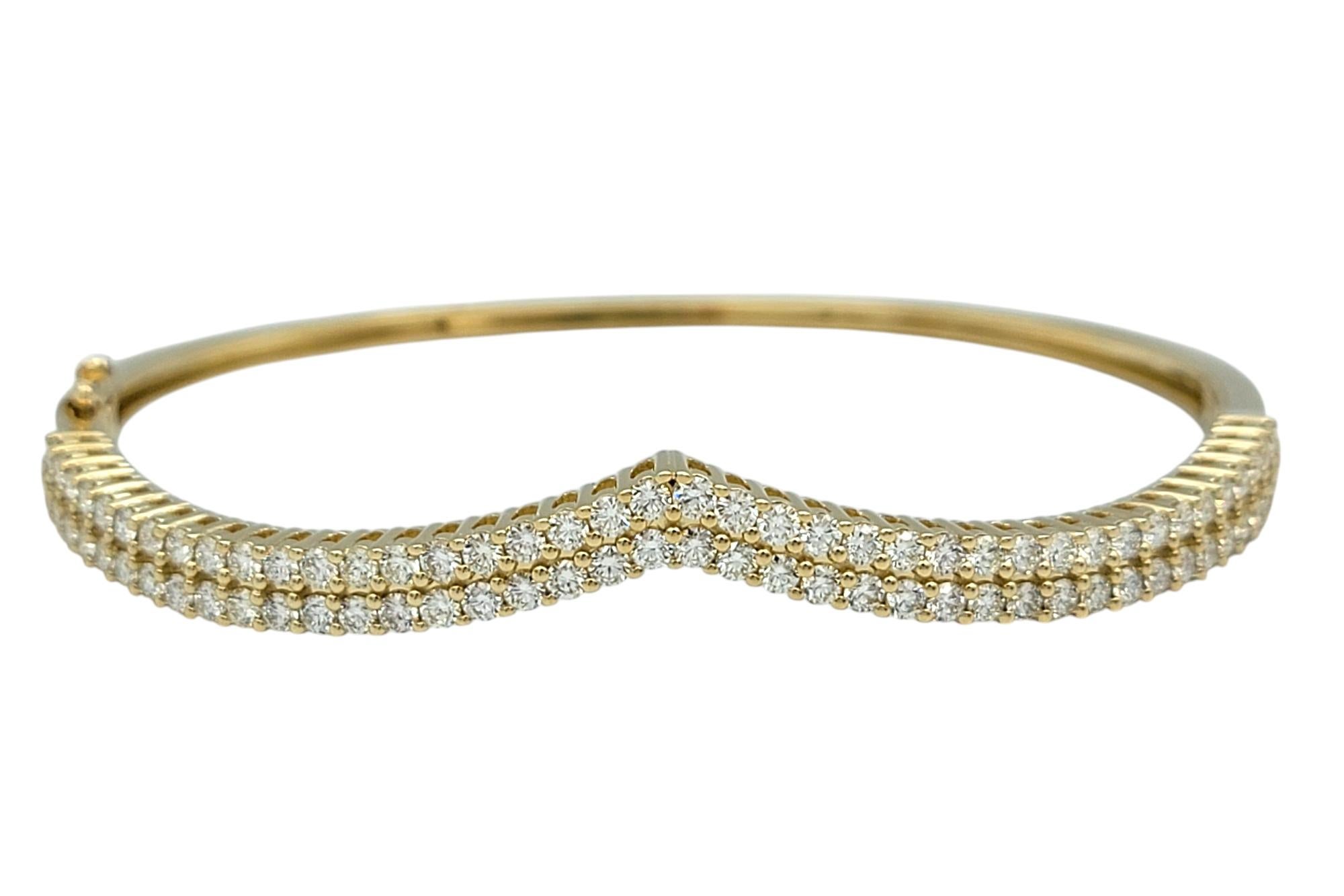 Elevate your jewelry collection with this exquisite chevron-style hinged bangle bracelet, crafted in 14 karat yellow gold. Designed with a sleek double-row of brilliant round diamonds, this piece offers a striking balance of modern elegance and