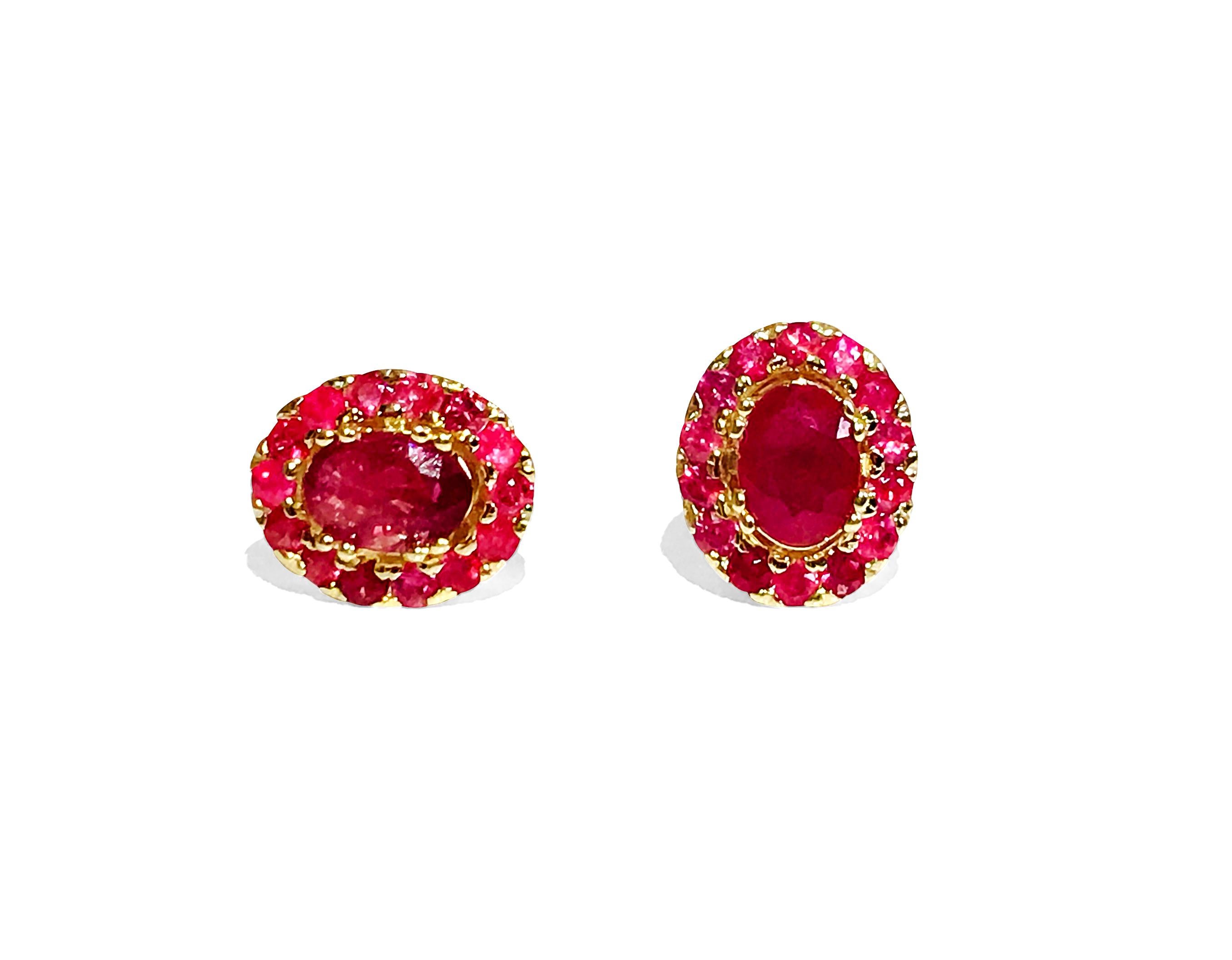 These are gold earrings with a big red stone in the middle and smaller ones on the sides. The main stone is 2.00 carats, and the smaller stones add up to 1.12 carats. In total, all the stones together weigh 3.12 carats. The red stones are real and