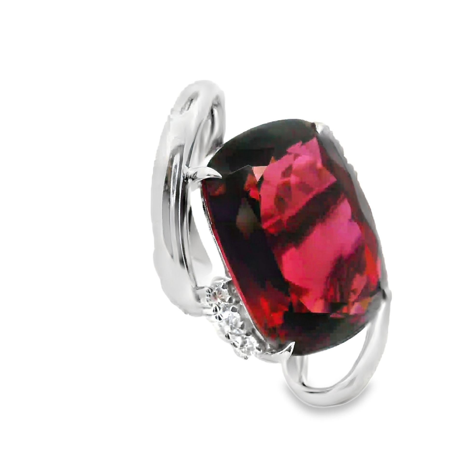 A large and exceptional ring featuring a massive cushion-shape tourmaline weighing 31.41 carats. It has a vibrant pink color with excellent brilliance as the crystal is pure and clean with no visible inclusions at all. It is complemented by 6 round