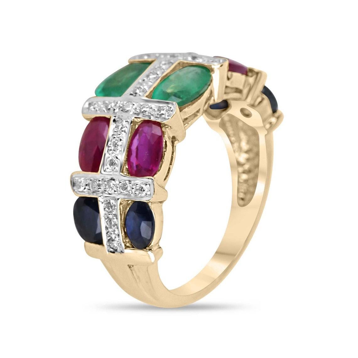 This vibrant statement ring features oval-cut emeralds, rubies, and sapphires, beautifully alternating and set east-to-west for a bold, colorful display. The spaces between the gemstones are filled with dazzling diamond clusters, arranged in an
