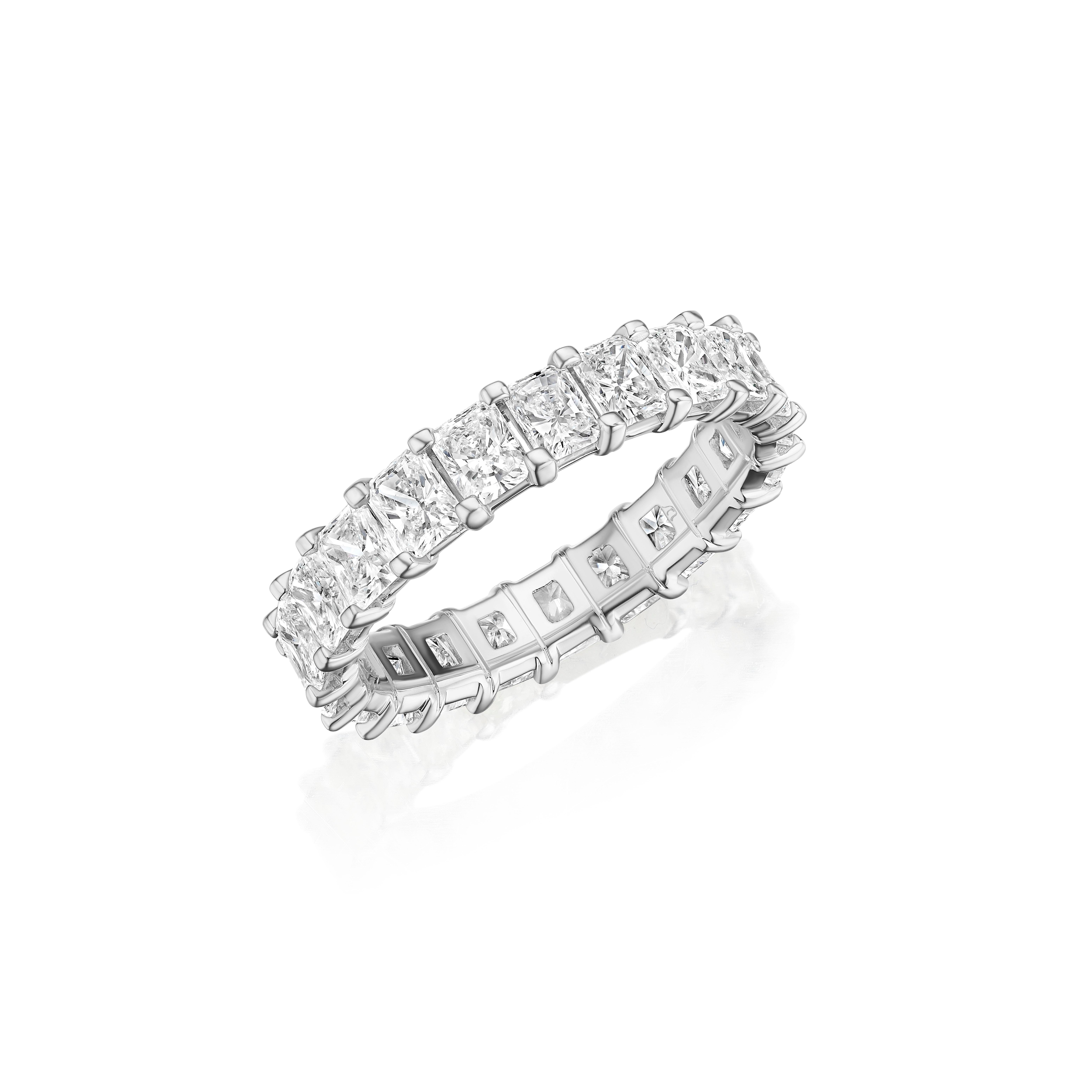 • Crafted in 18KT gold, this eternity band is made with 21 radiant cut diamonds, and has a combining total weight of approximately 3.15 carats. The diamonds are set into a shared prong basket setting. Worn beautifully on its own or stacked. A